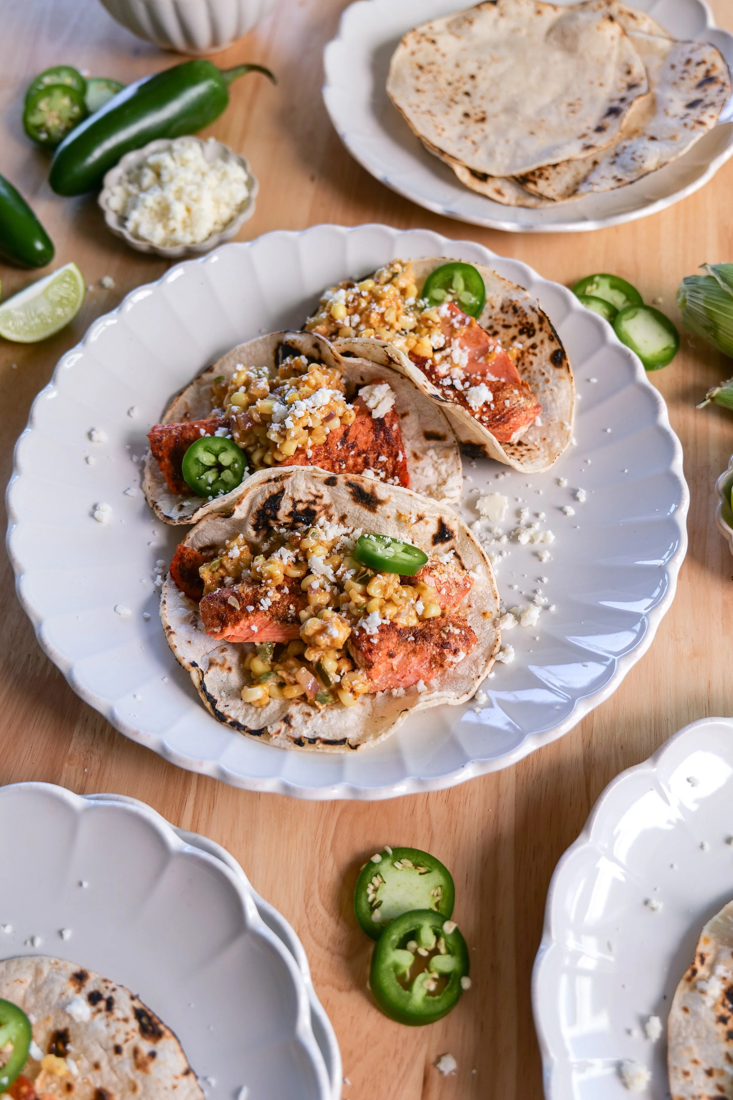 Close-up of salmon tacos with fresh corn salsa, red onion, jalapeño, and cotija