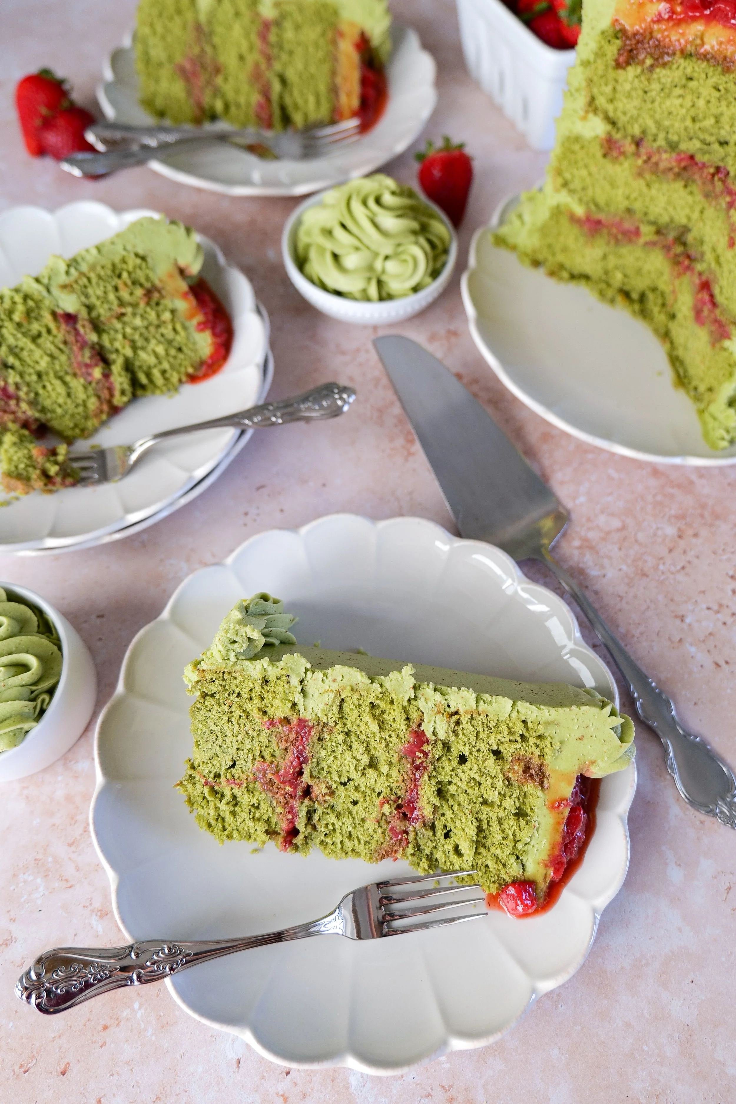 Green tea matcha strawberry cake slices served with fresh strawberries and buttercream