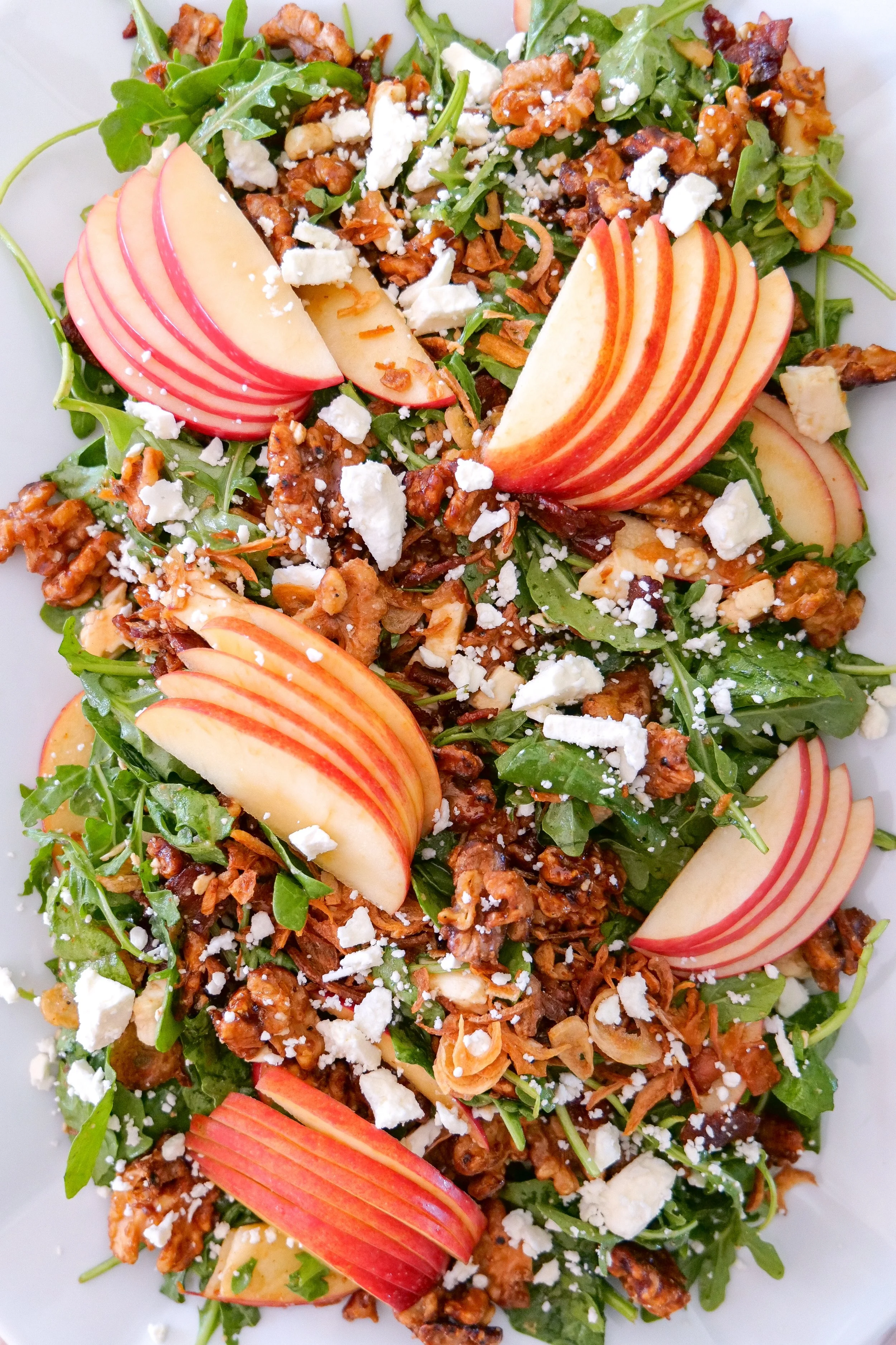 Colorful fall harvest salad with apples, bacon, feta, walnuts and crispy shallots.