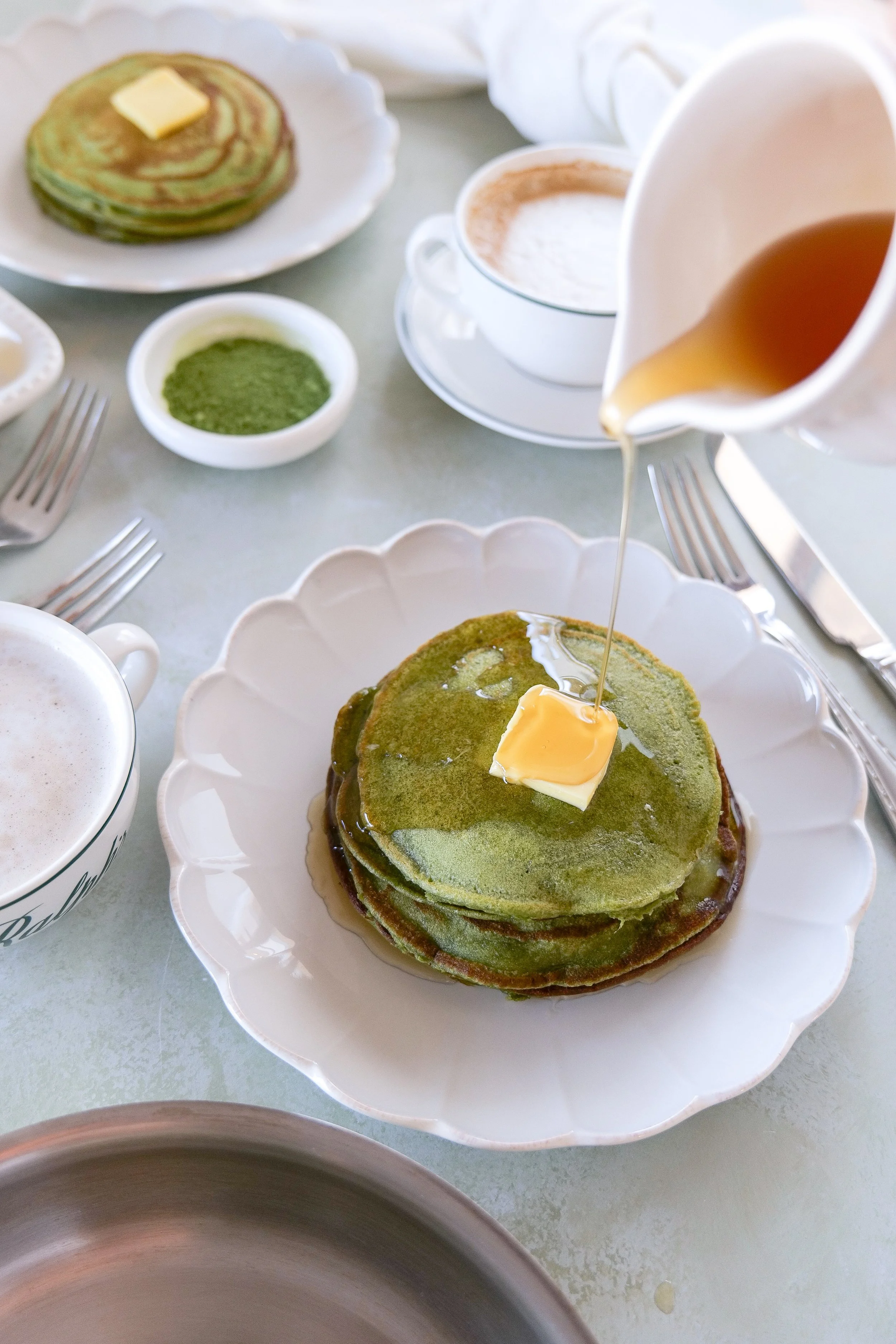 Stack of matcha sourdough discard pancakes with syrup pouring