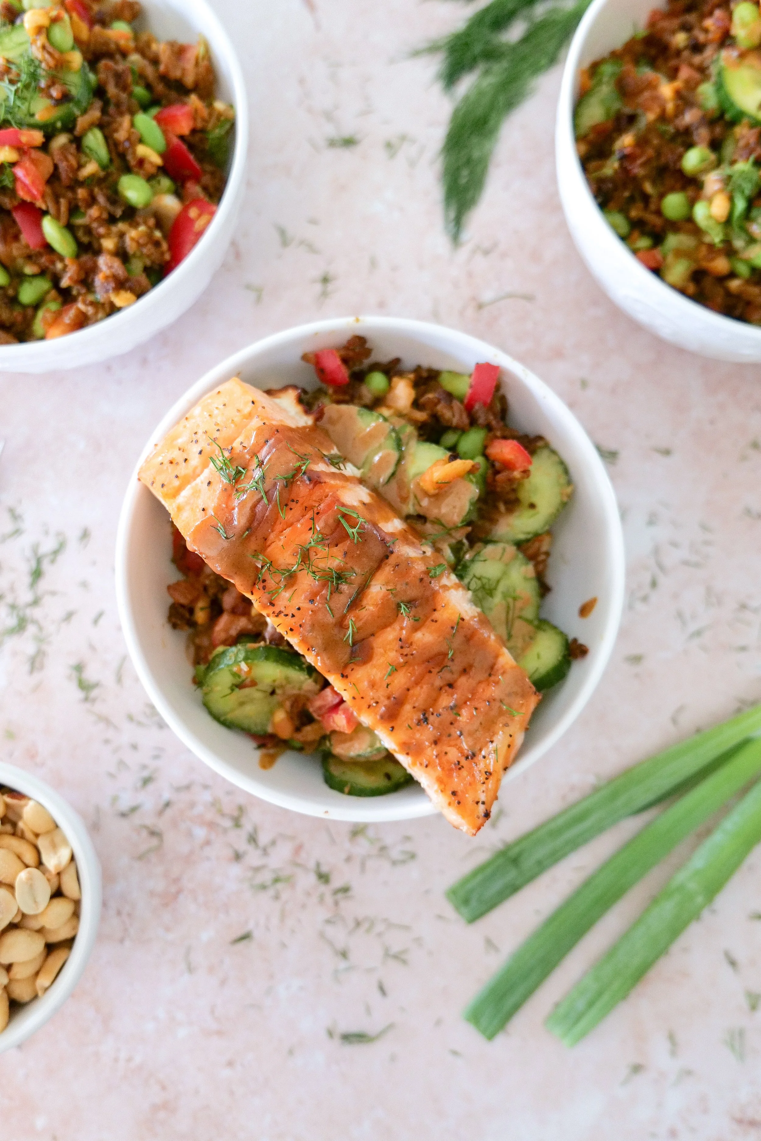 Pan-seared salmon seasoned with salt and pepper over a colorful crispy rice salad.