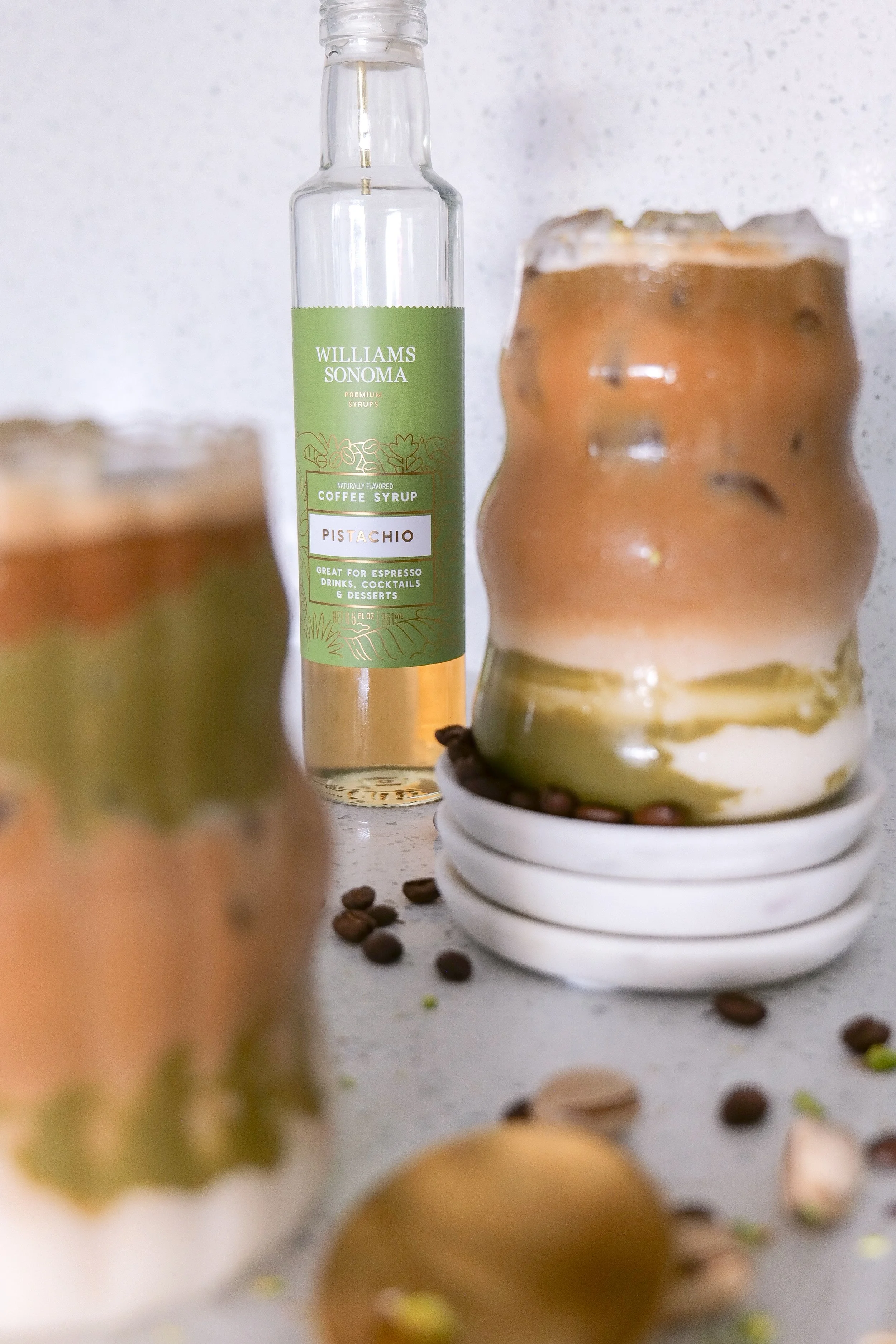 Layered iced pistachio latte showing creamy milk and dark espresso in a tall glass.