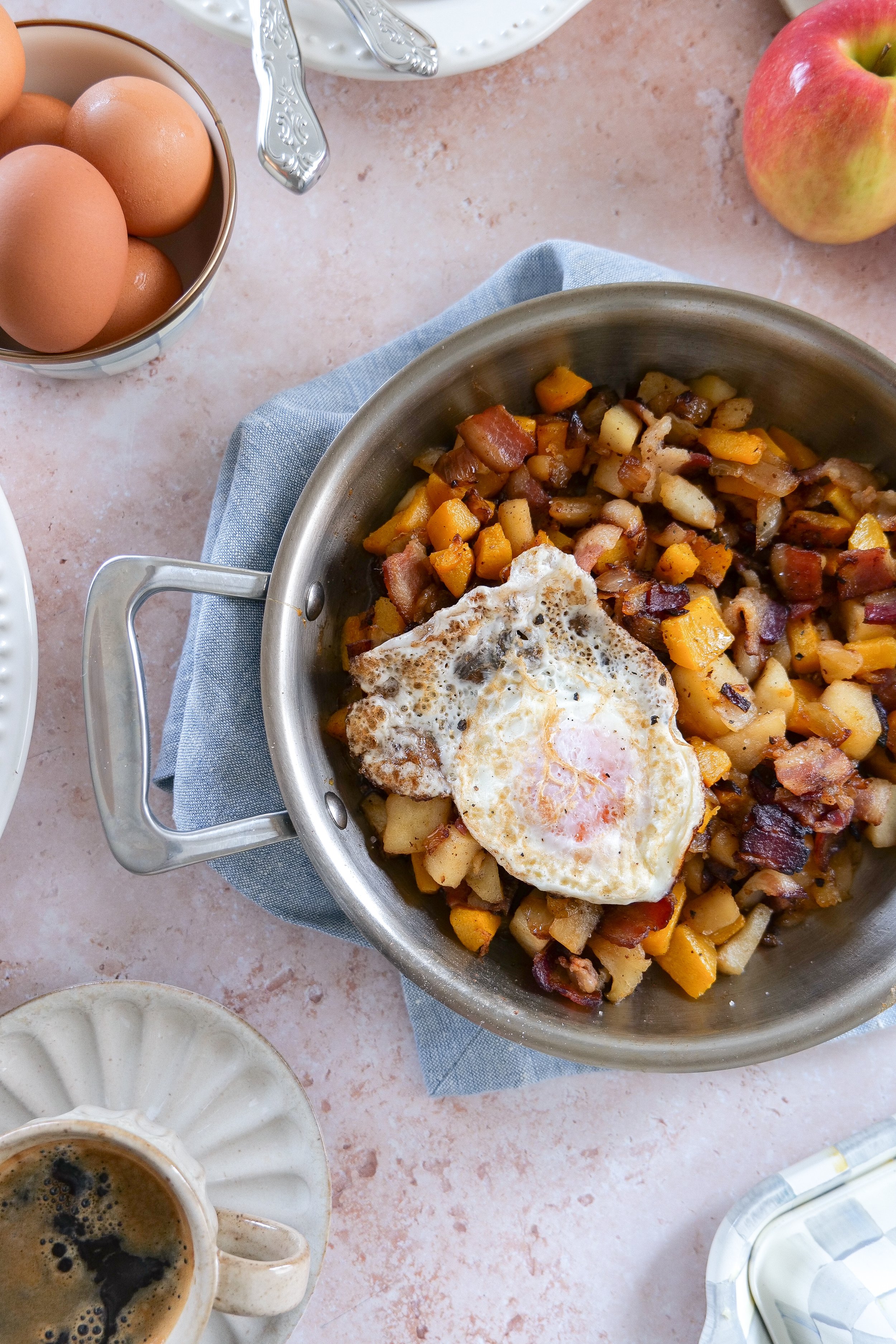 Sweet and savory fall breakfast hash with butternut squash, apples, bacon, and fried eggs.