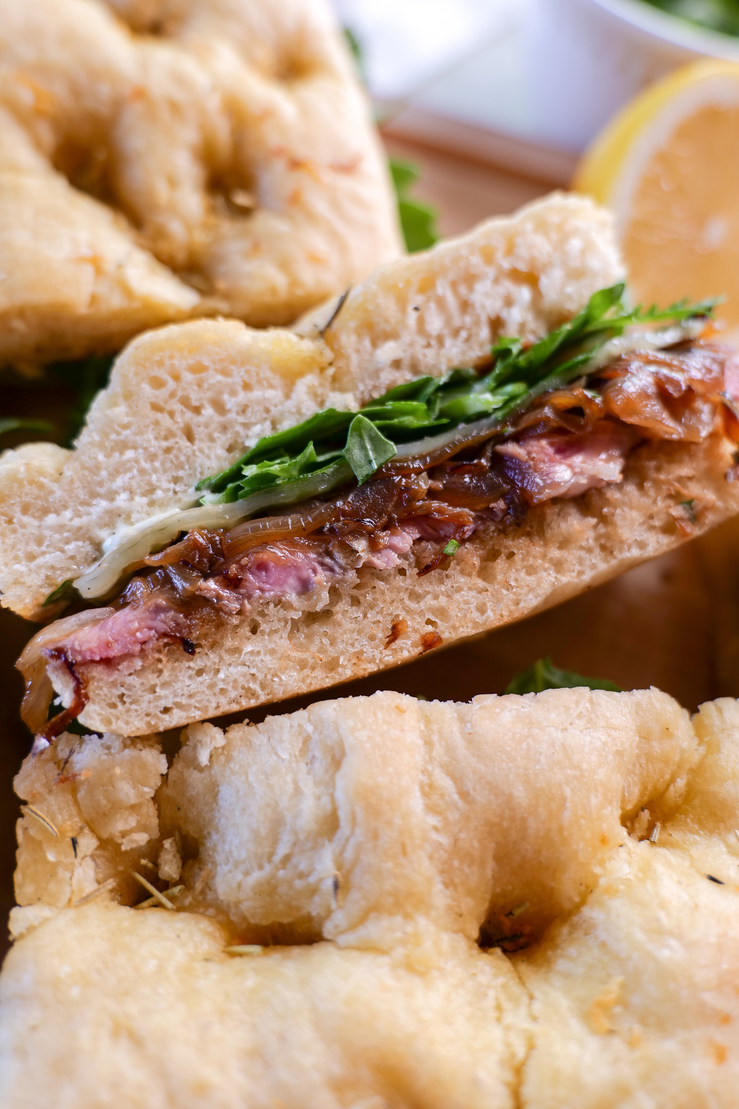 Steak focaccia sandwich cut in half showing ribeye, provolone and onions