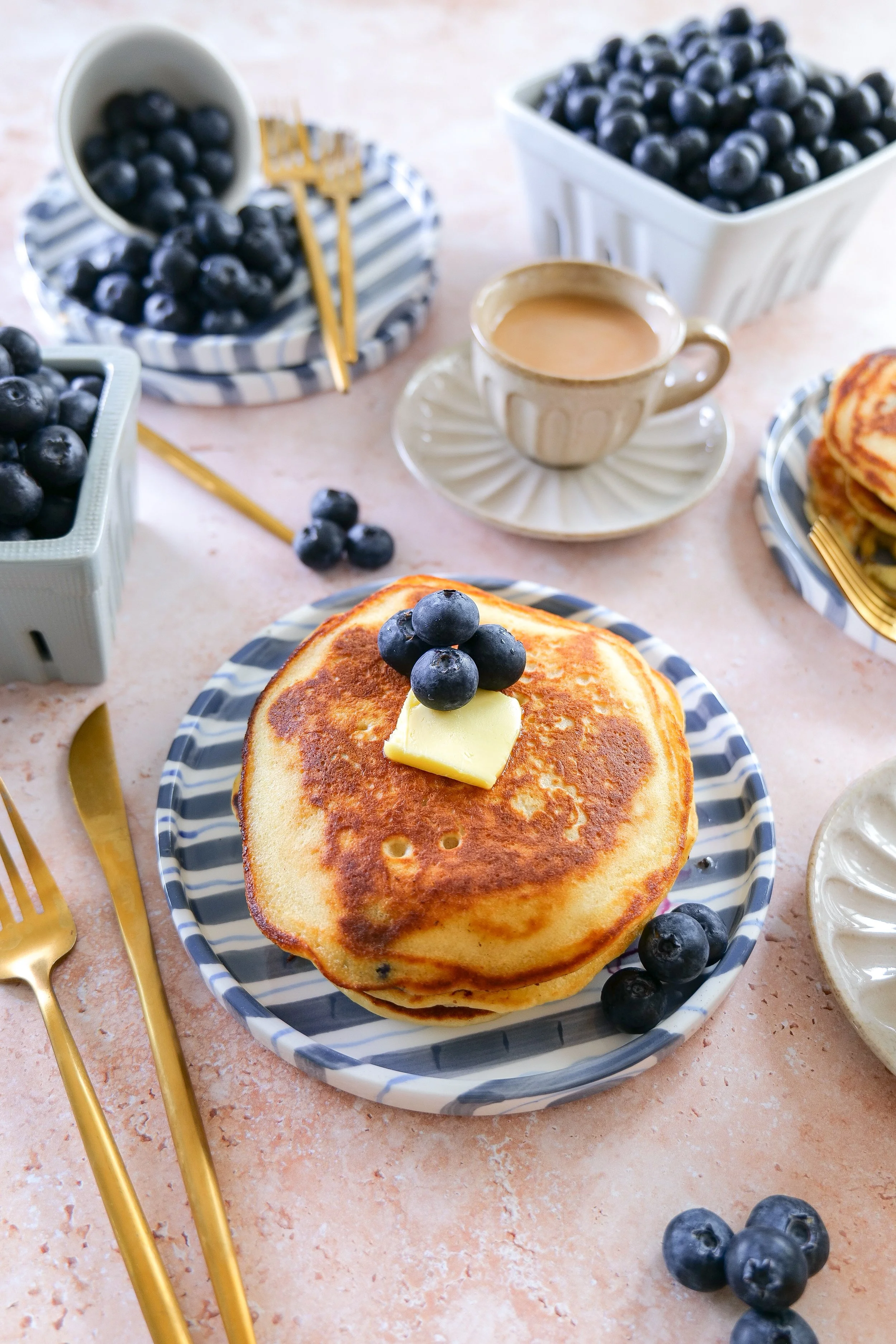 Blueberry pancakes stacked on a plate with maple syrup drizzle.