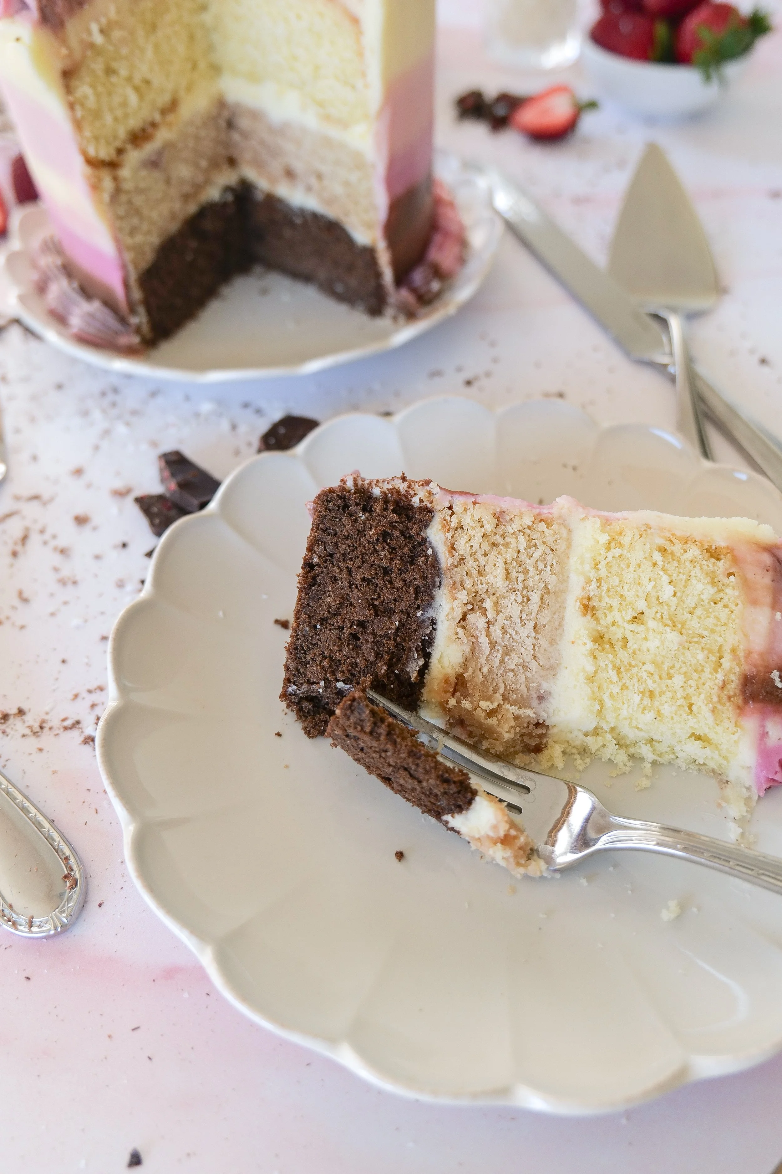 Slice of Neapolitan cake showing distinct chocolate, vanilla, and strawberry layers.