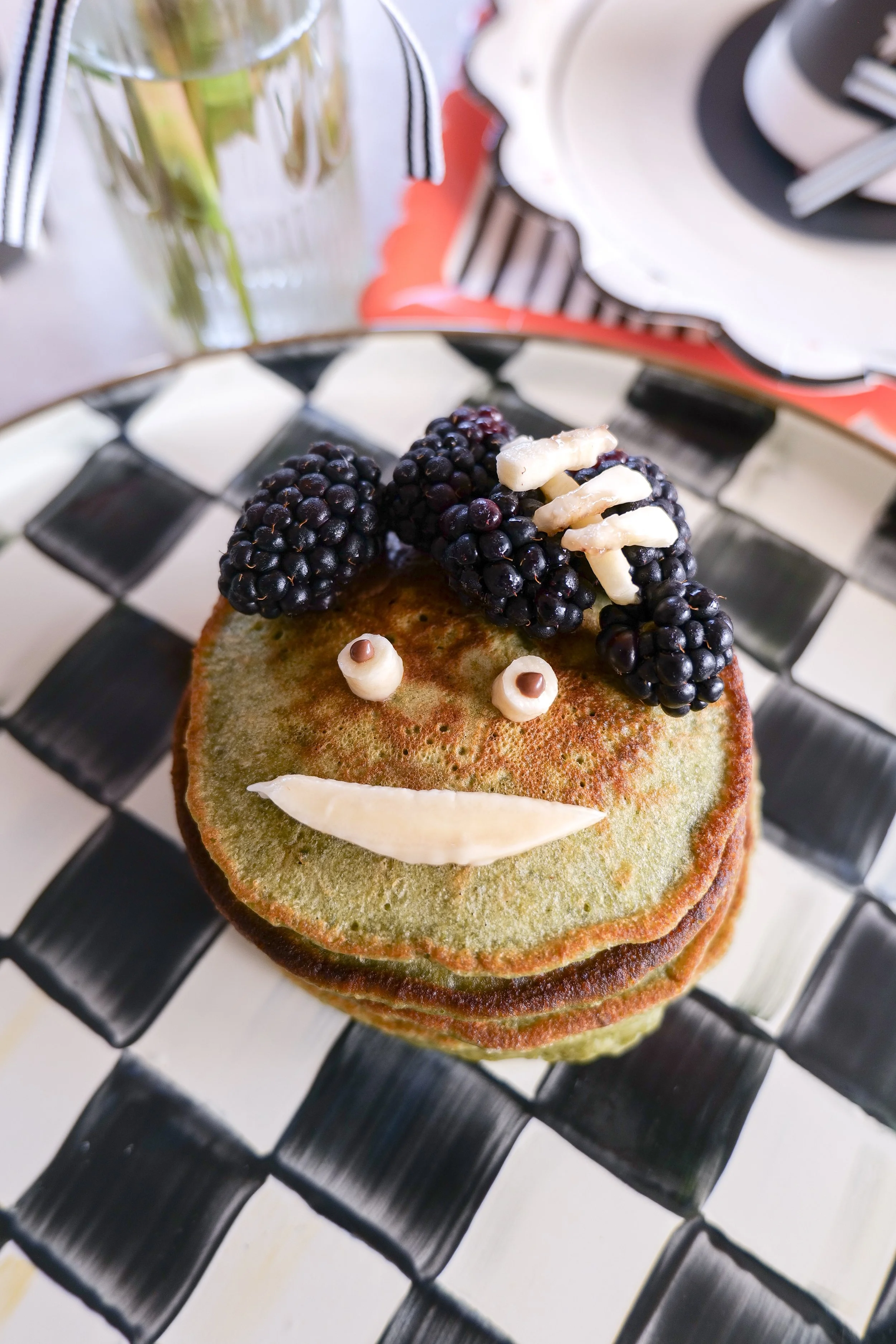 Green matcha Frankenstein pancake decorated with blackberries, banana and melted chocolate.
