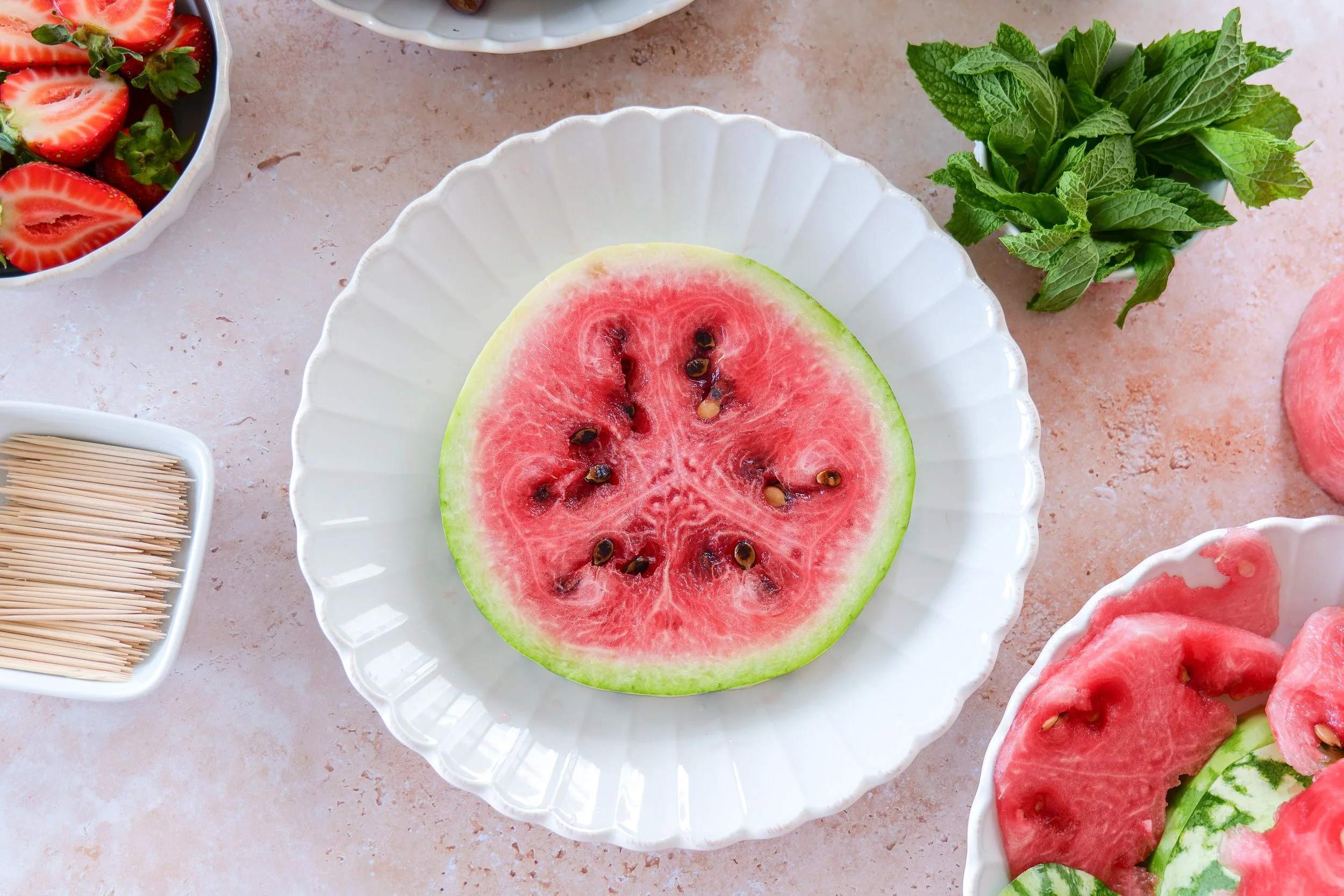 Seedless watermelon being trimmed into a round cake-shaped tier for an easy no-bake fruit cake.