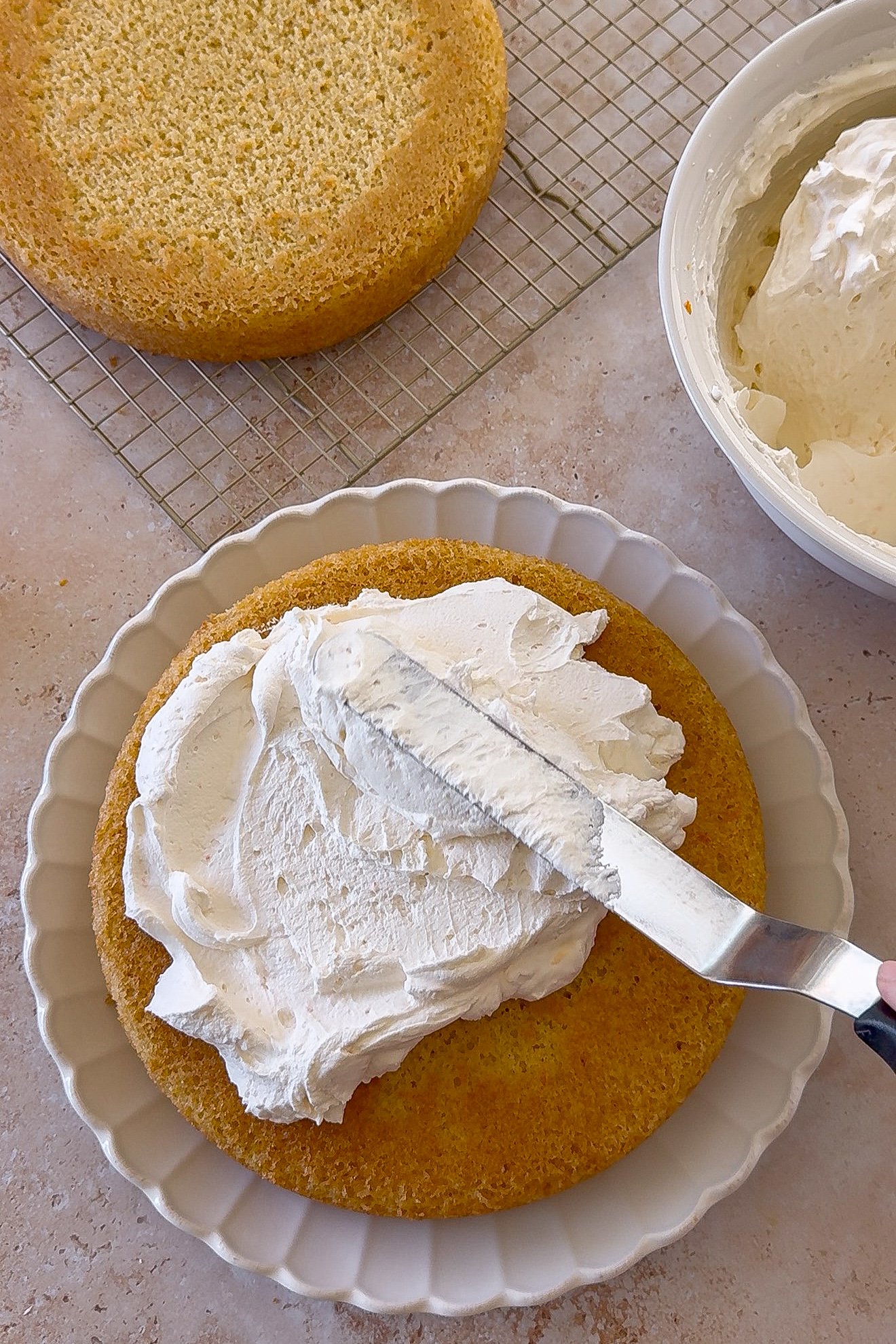 Mascarpone cream spread over the first layer of orange olive oil cake