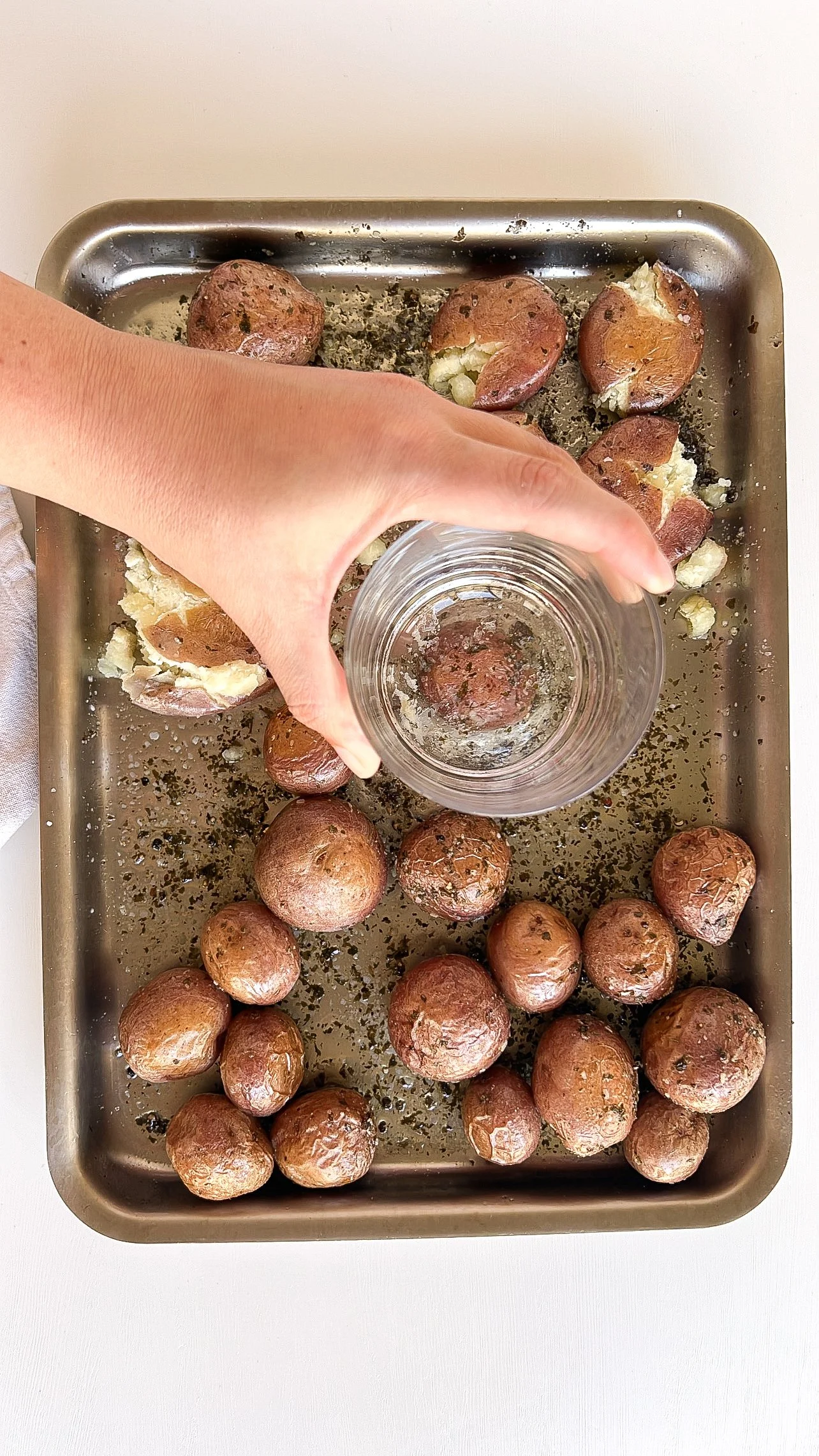 Flattening roasted baby red potatoes with the bottom of a glass