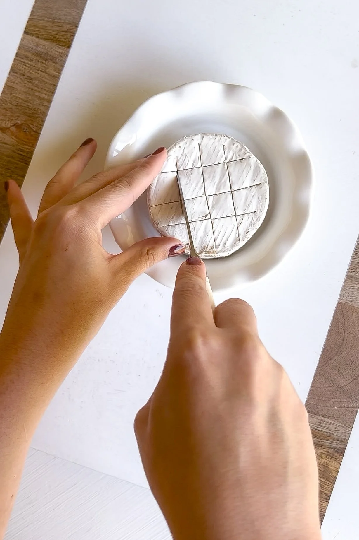 Wheel of Brie scored in a crosshatch pattern before baking
