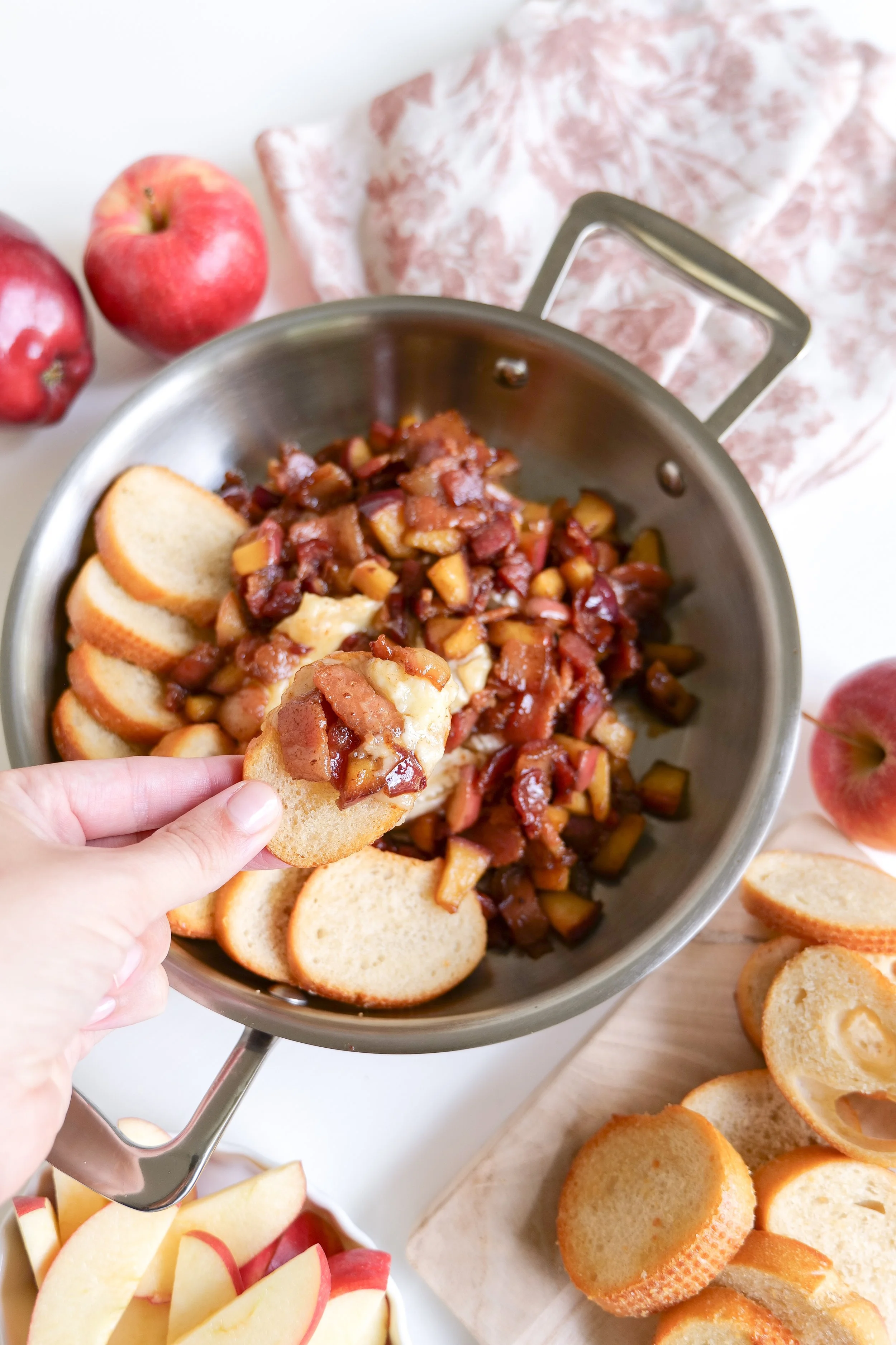 Warm baked brie topped with caramelized apples and crispy bacon on a serving platter.
