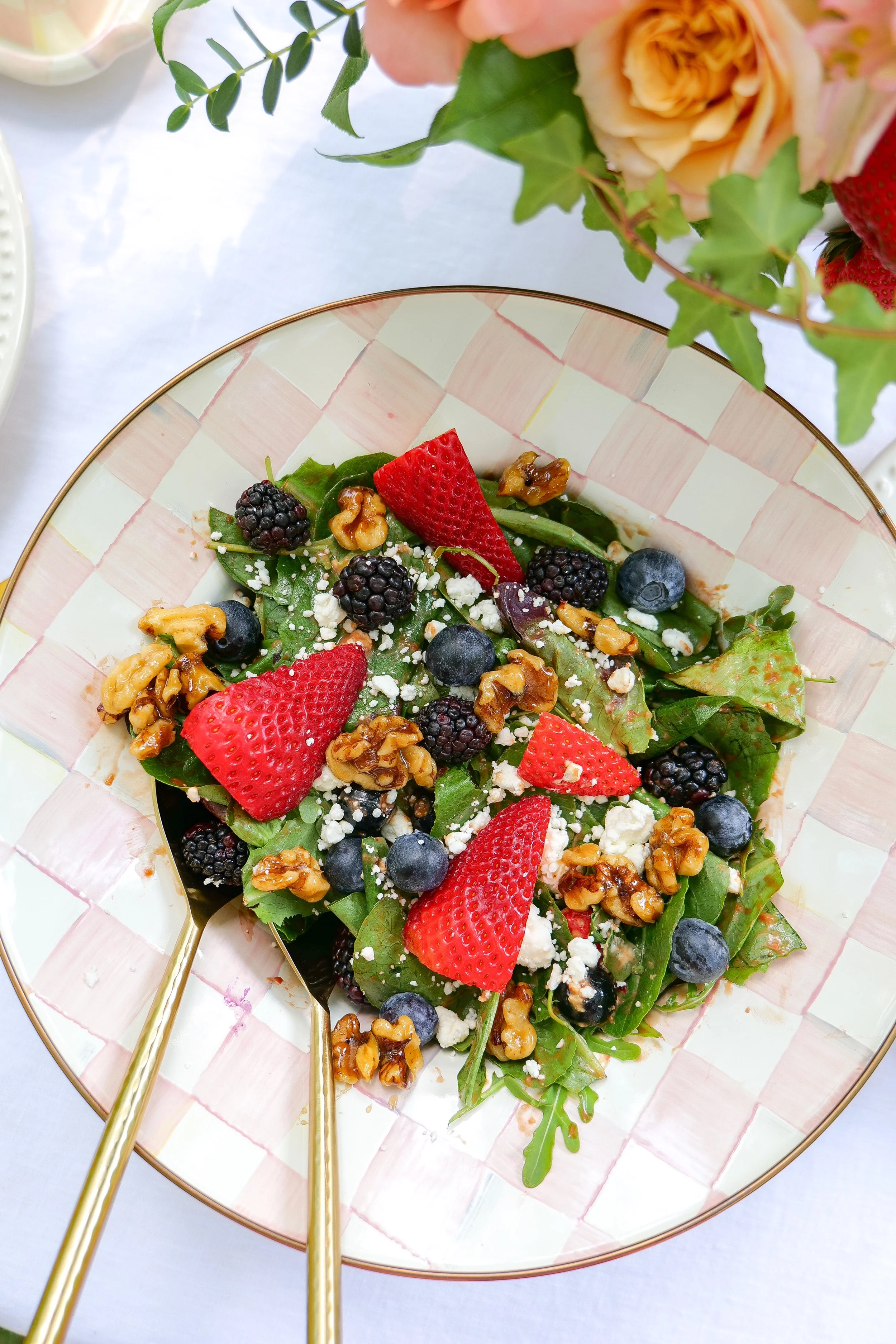 Berry goat cheese salad with strawberries, blueberries, blackberries and candied walnuts served at an outdoor garden table.