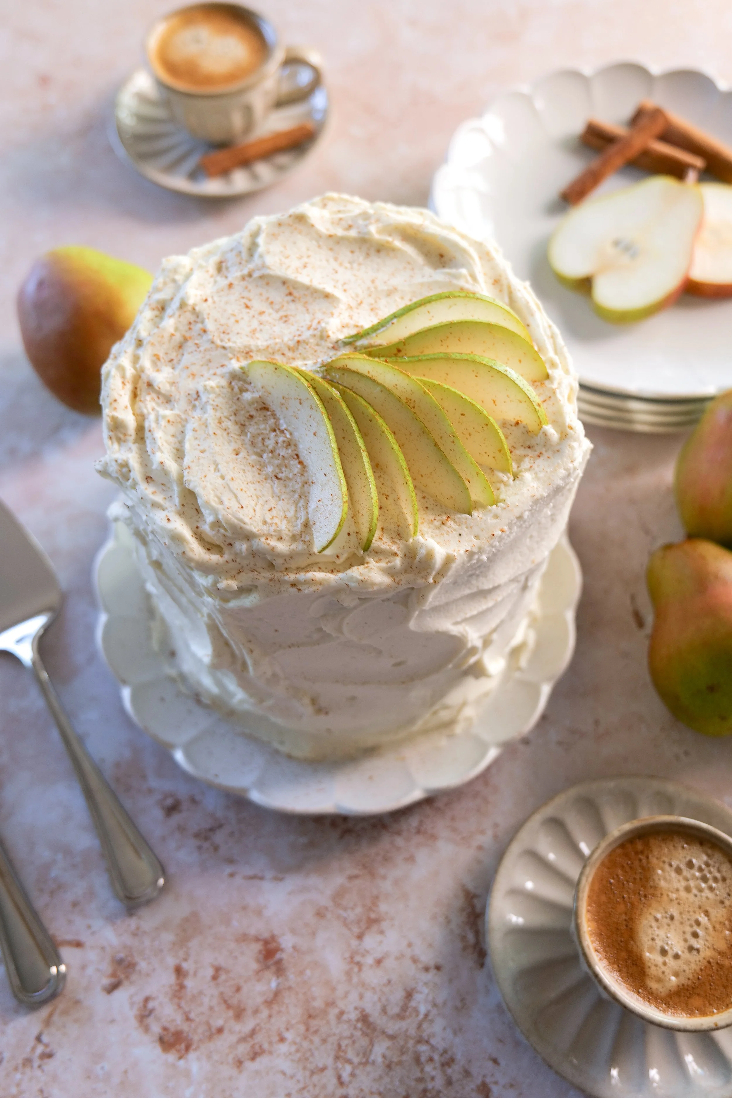 Three-layer pear cake covered in vanilla mascarpone cream and topped with fresh pears.