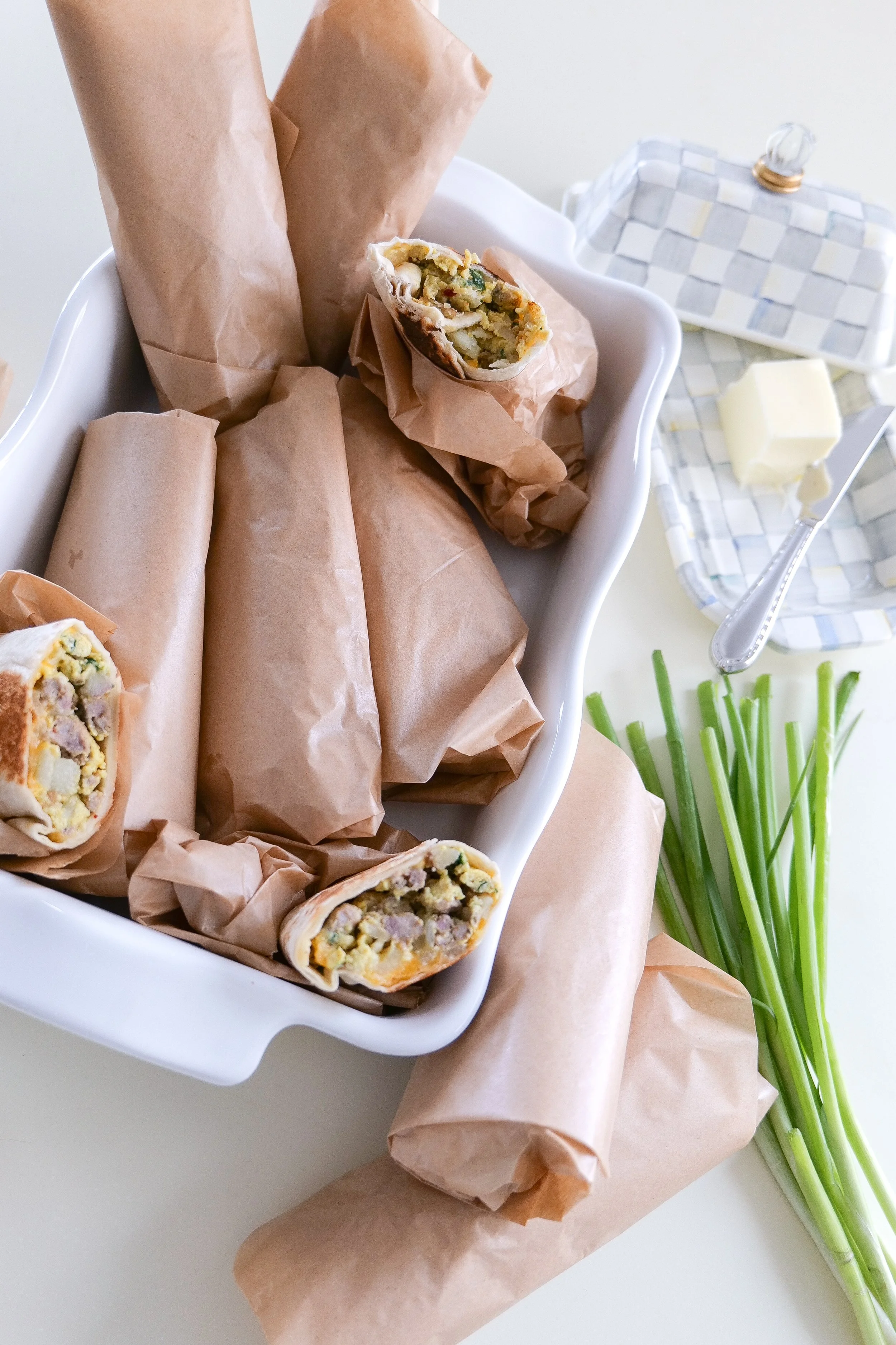 Meal prep breakfast burritos filled with seasoned potatoes, breakfast sausage, eggs, spinach and shredded cheese.