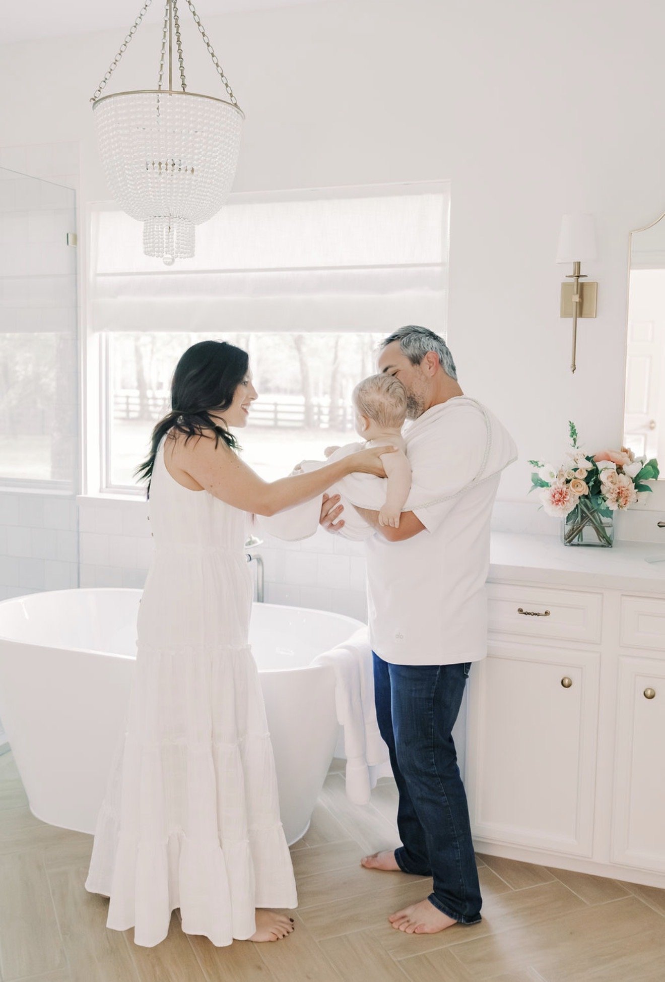Mom and dad holding their baby wrapped in a towel after bath time in their Texas home