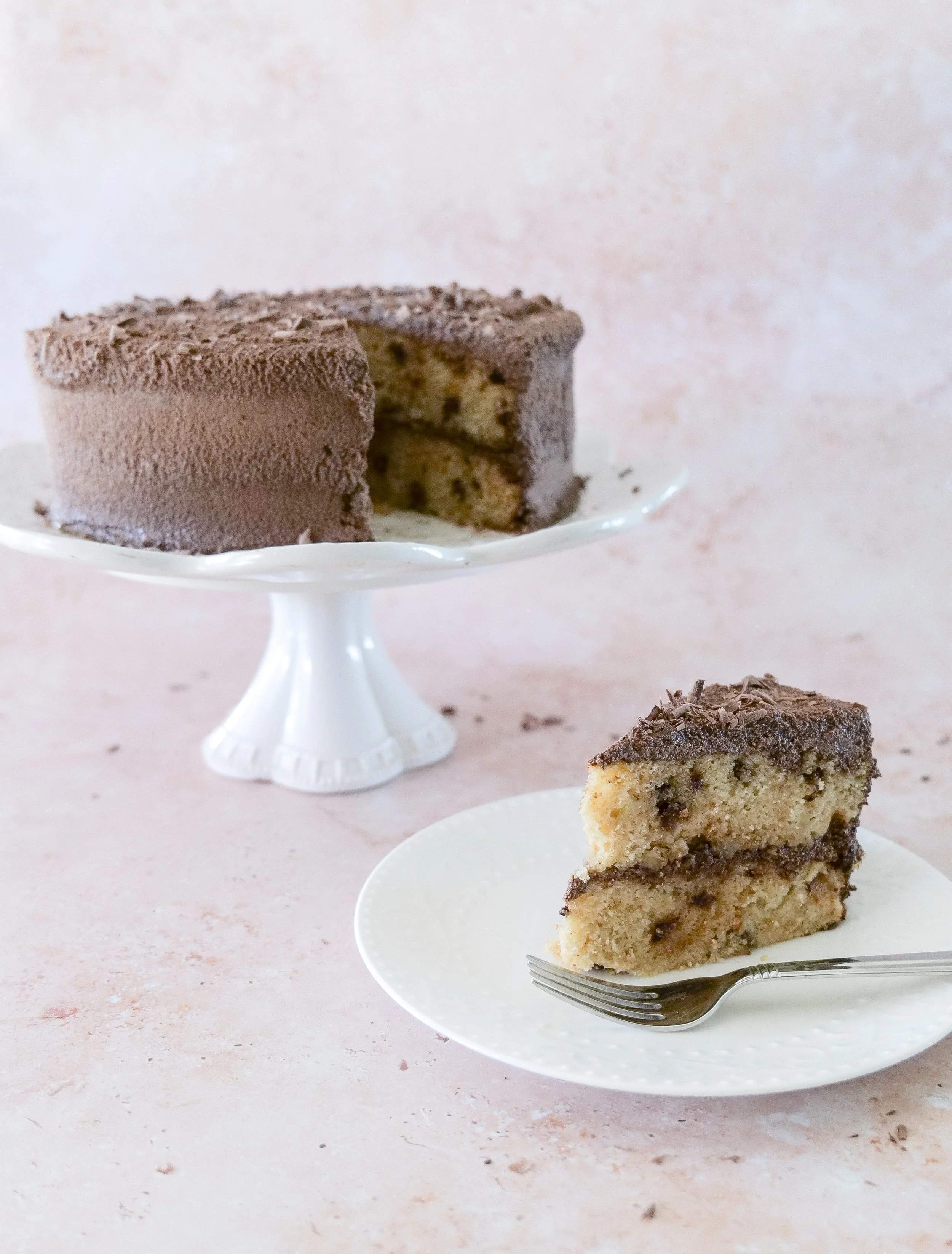 Slice of banana chocolate chip layer cake showing banana cake and chocolate ganache layers.