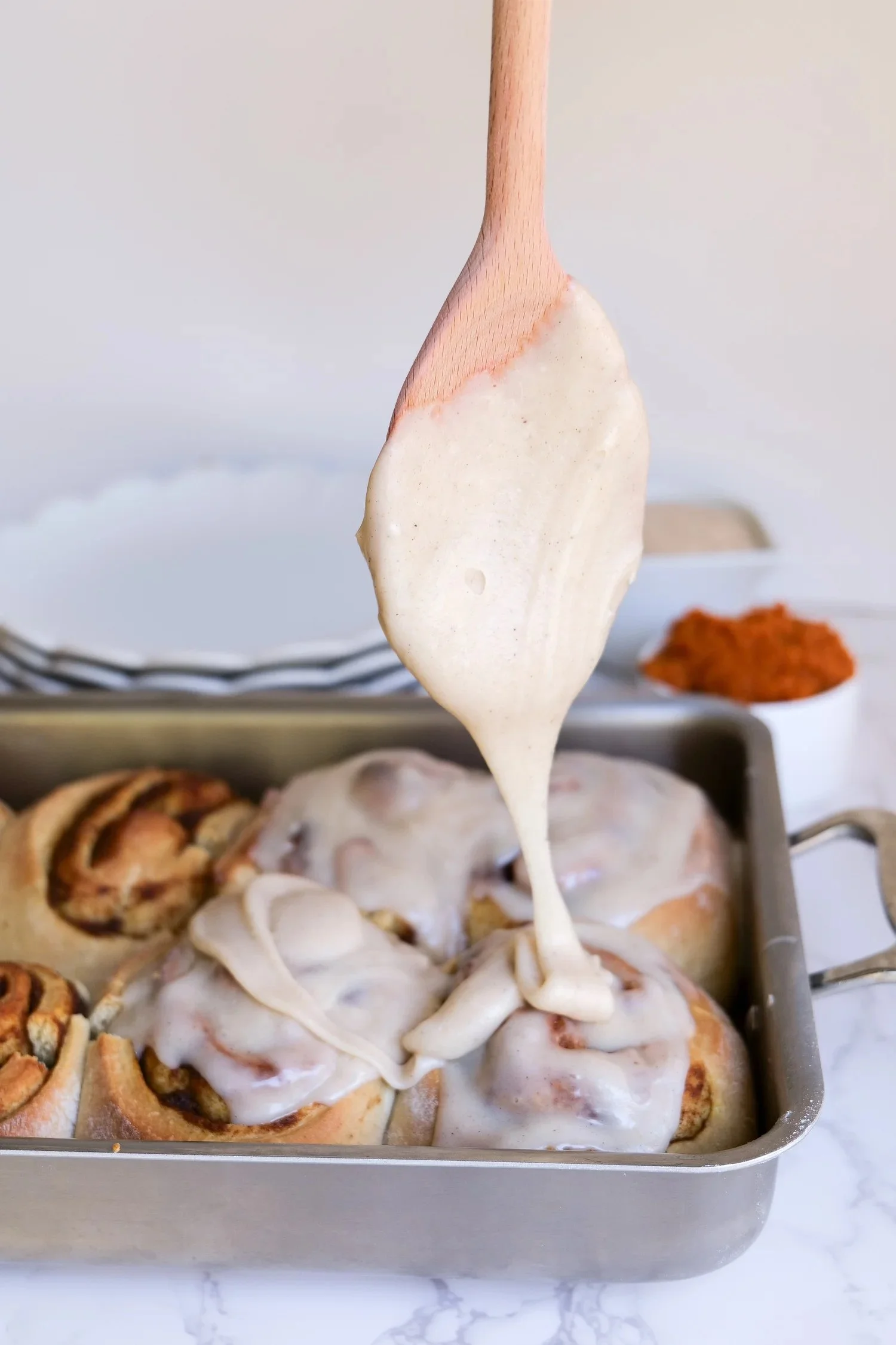 Homemade pumpkin cinnamon rolls topped with cream cheese icing.