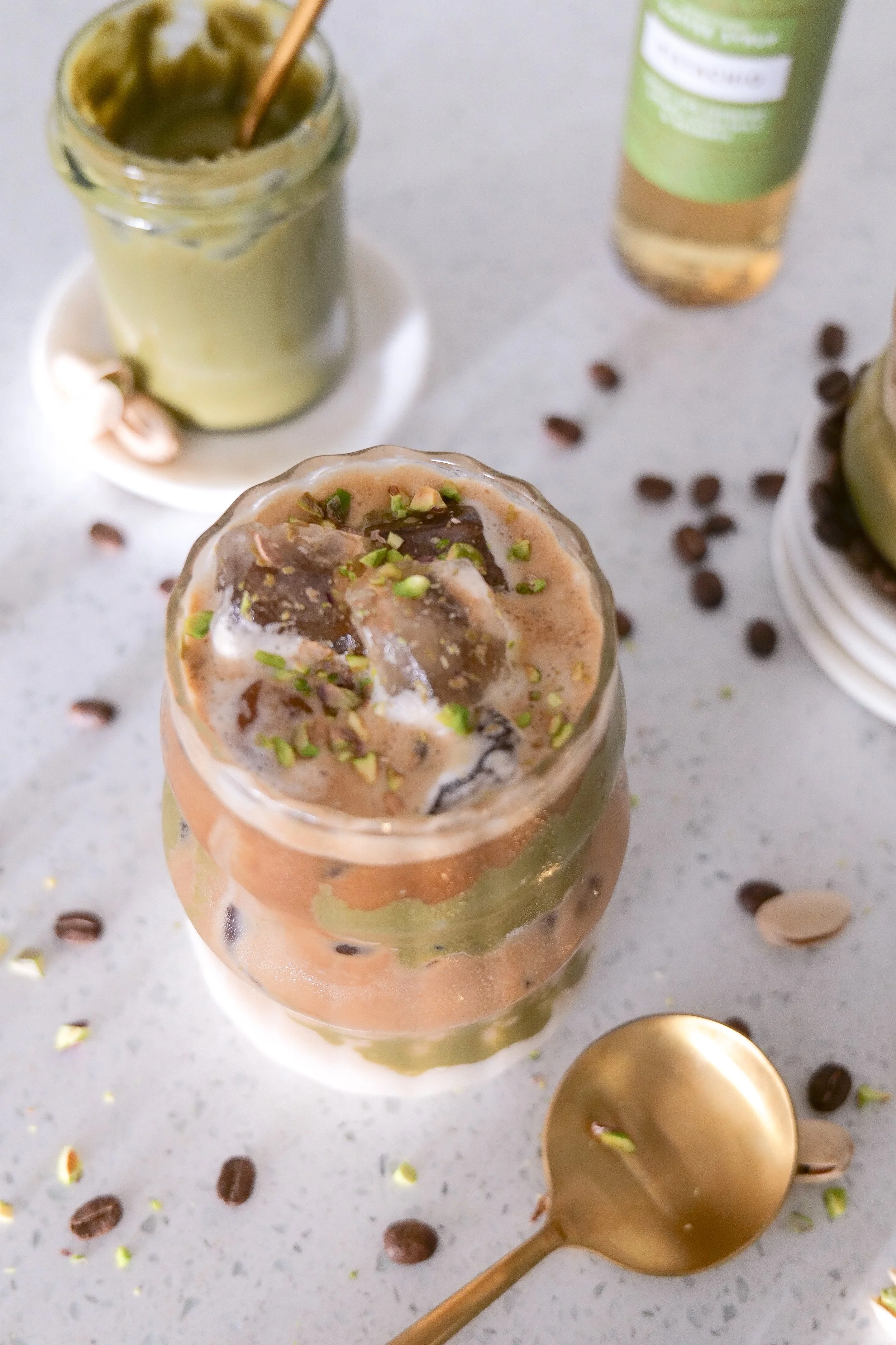 Iced pistachio latte served in a clear glass to show the creamy coffee layers.
