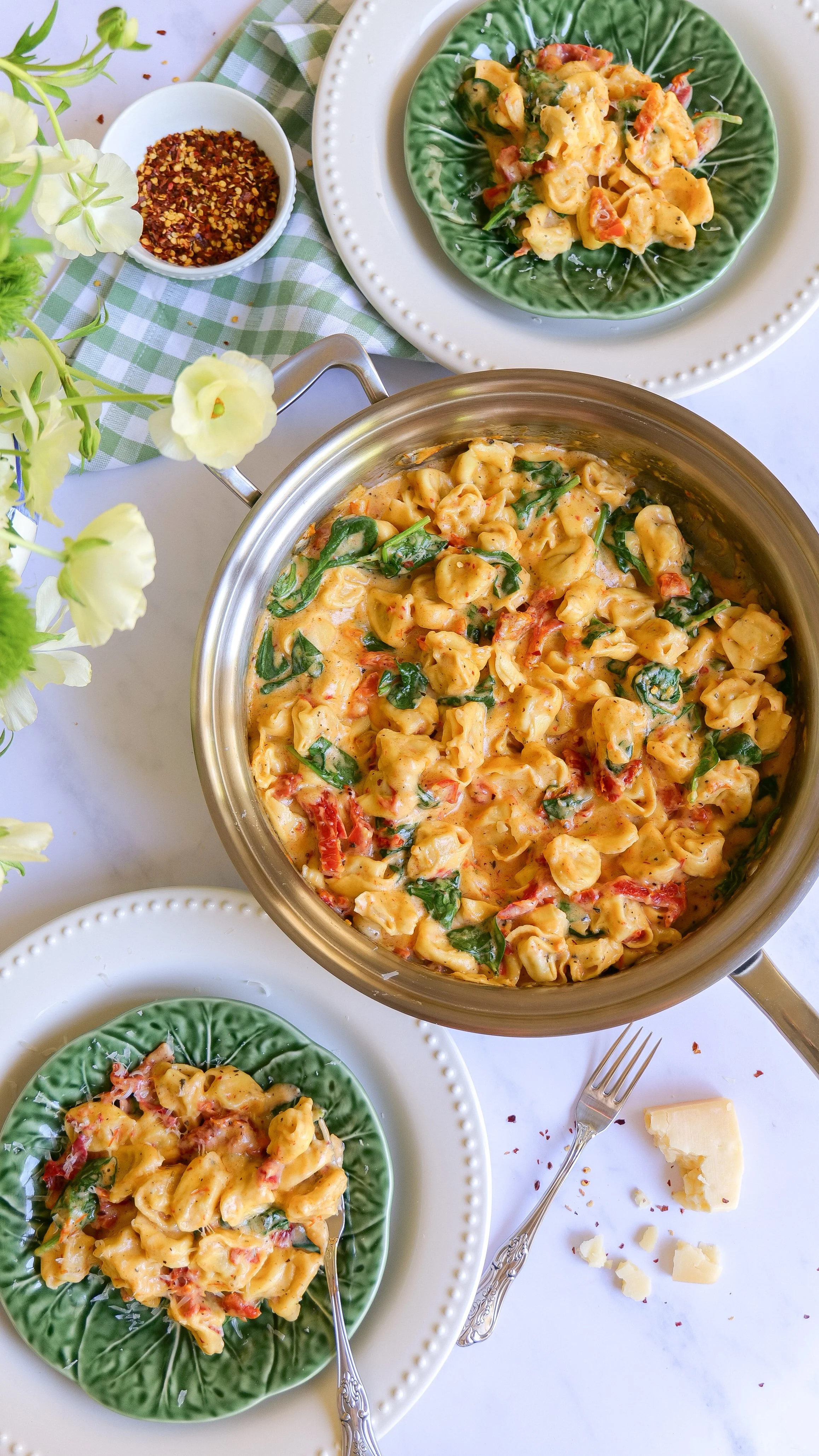 One Pot Marry Me Tortellini being spooned onto plates at a cozy dinner table