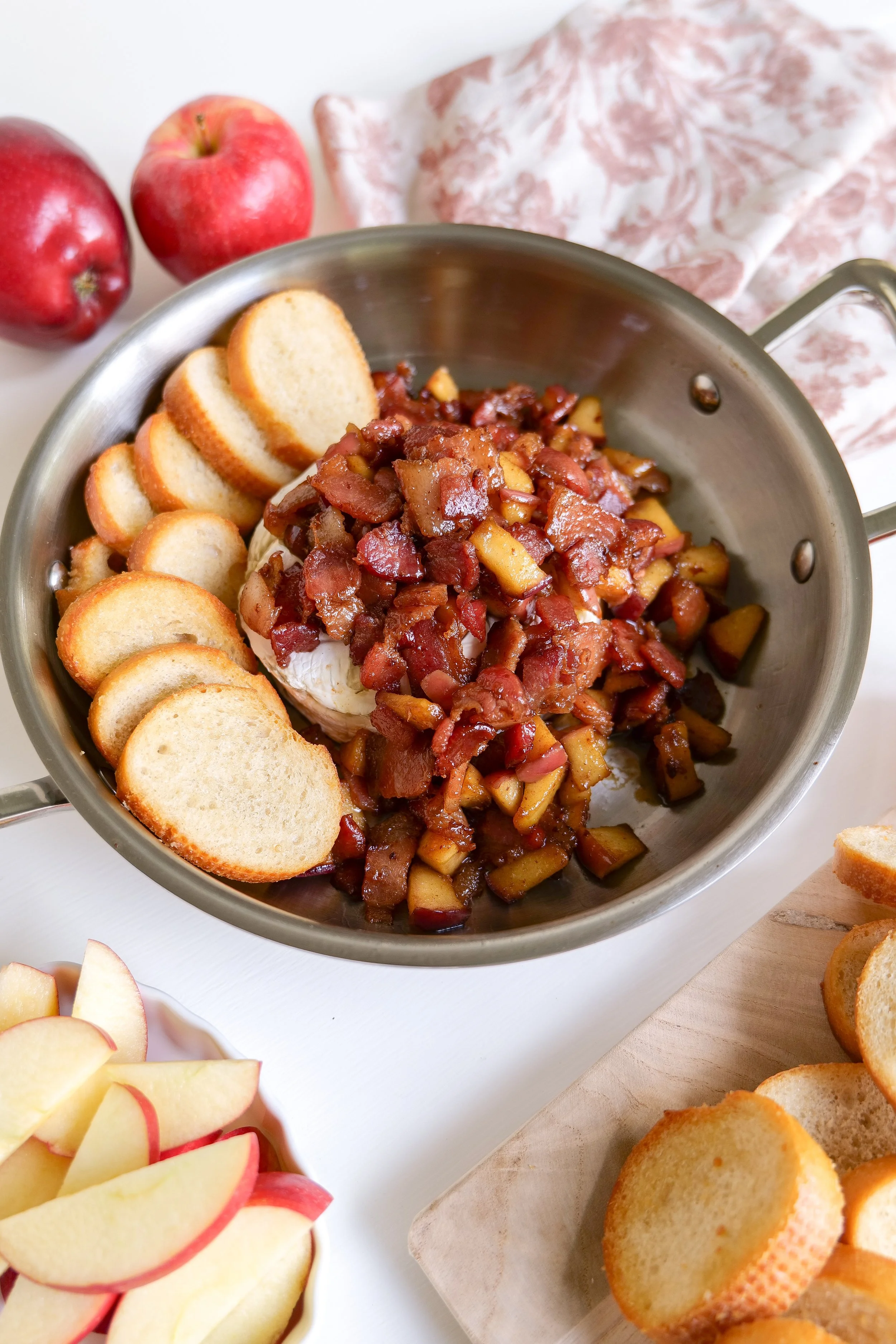 Easy bacon apple baked brie topped with crispy bacon, caramelized apples, and brown sugar served warm with crackers.