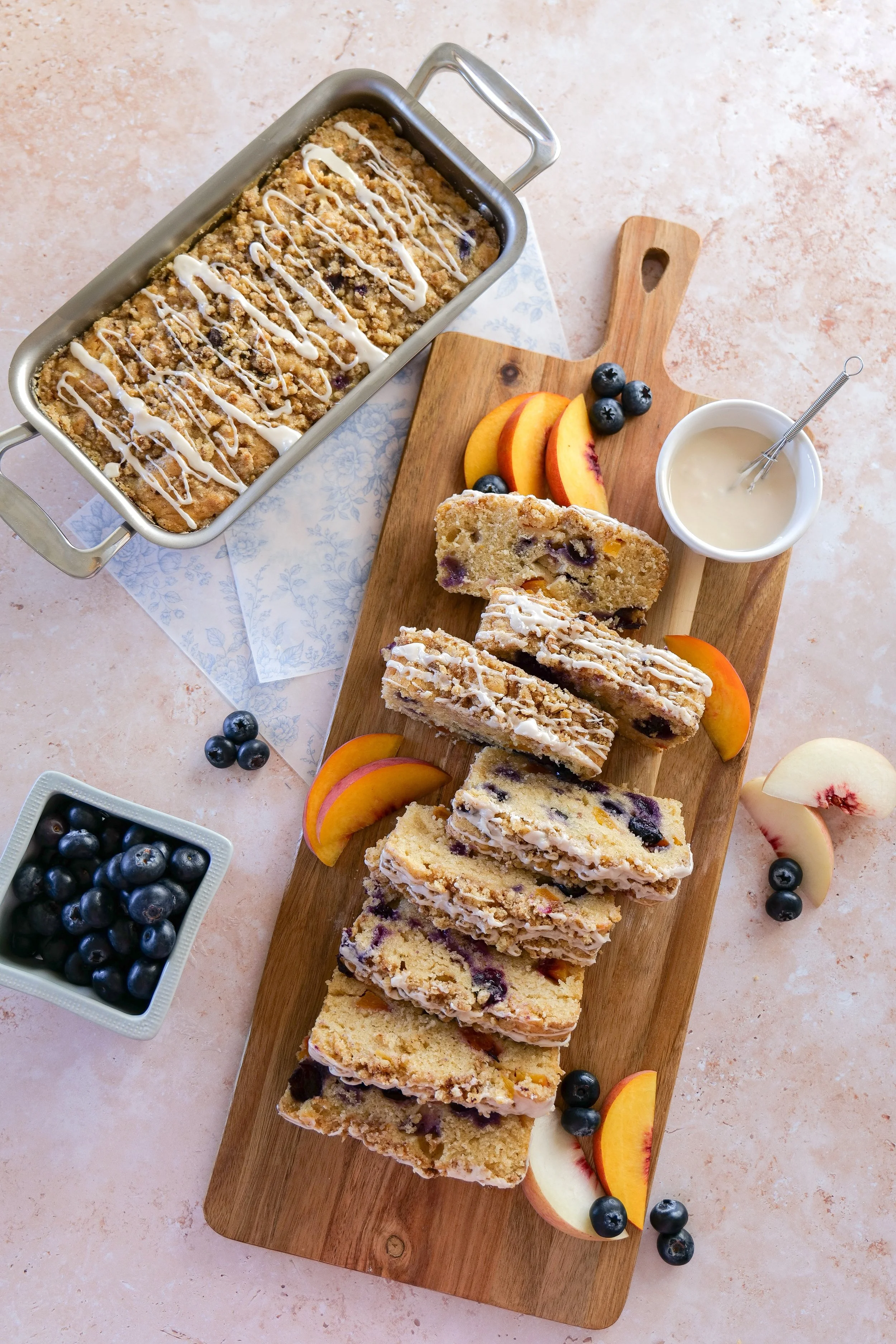 Close-up of a golden Blueberry Peach Streusel Loaf topped with vanilla glaze.