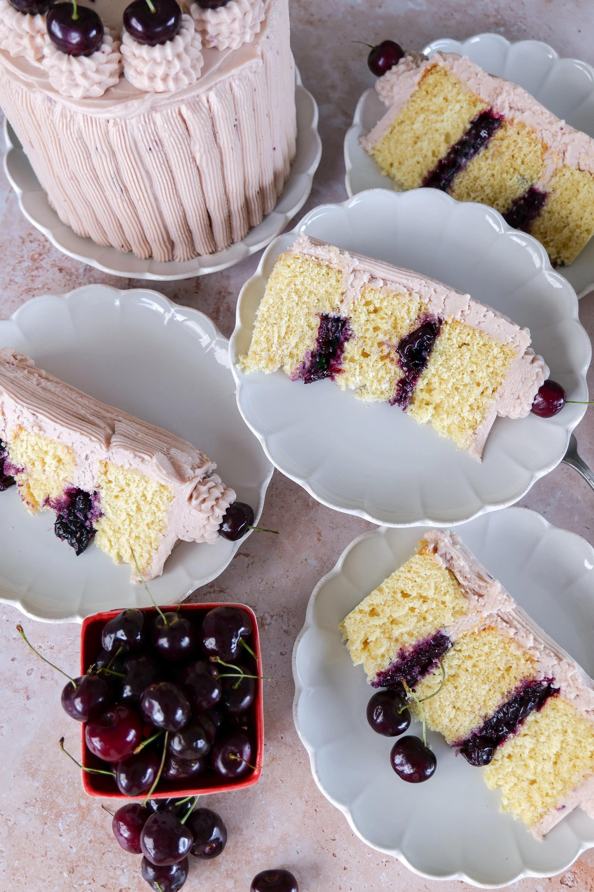 Homemade vanilla bean cherry layer cake decorated with fresh cherries and cherry buttercream.