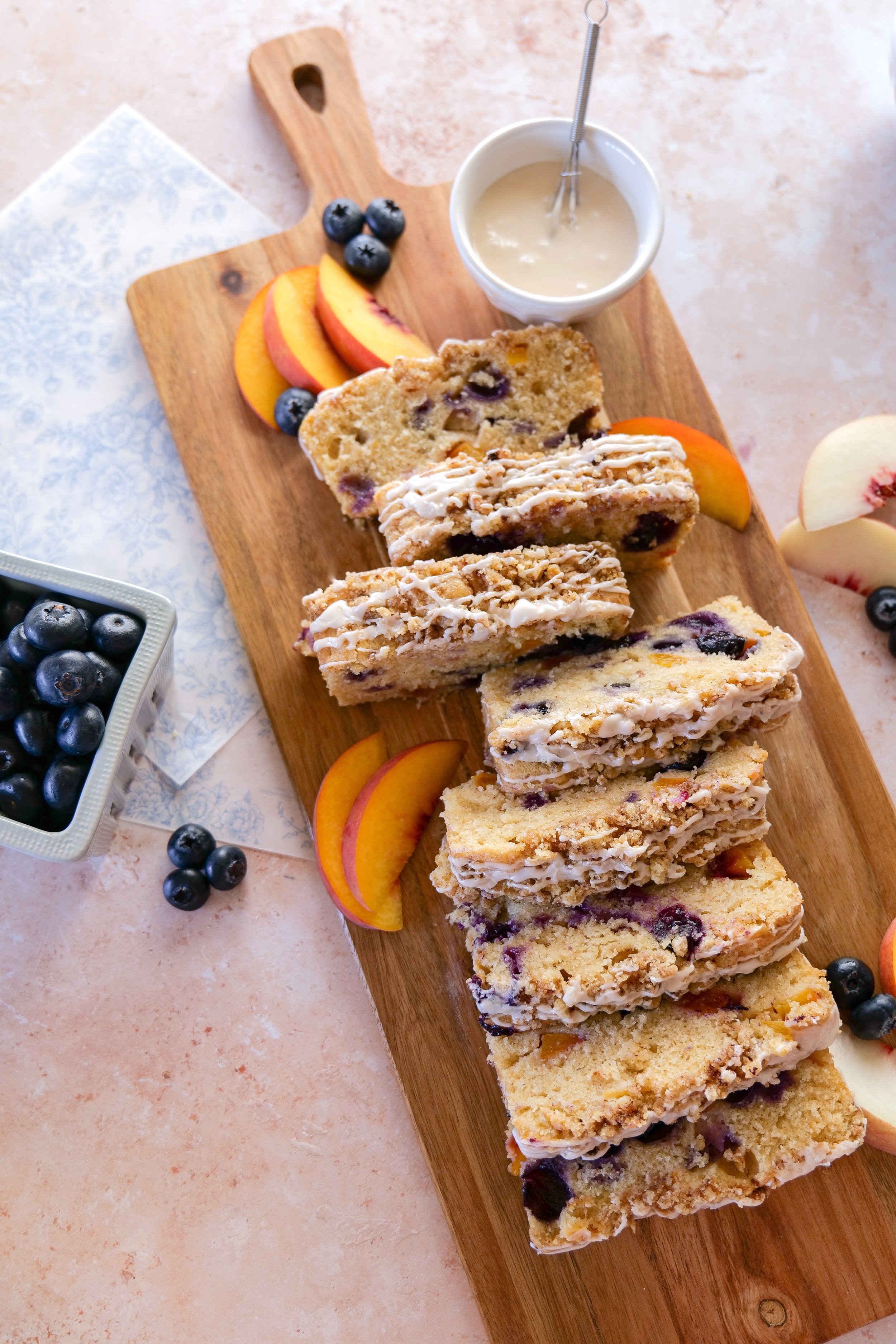 Cut Blueberry Peach Bread loaf showing a moist crumb filled with fresh peaches and blueberries.