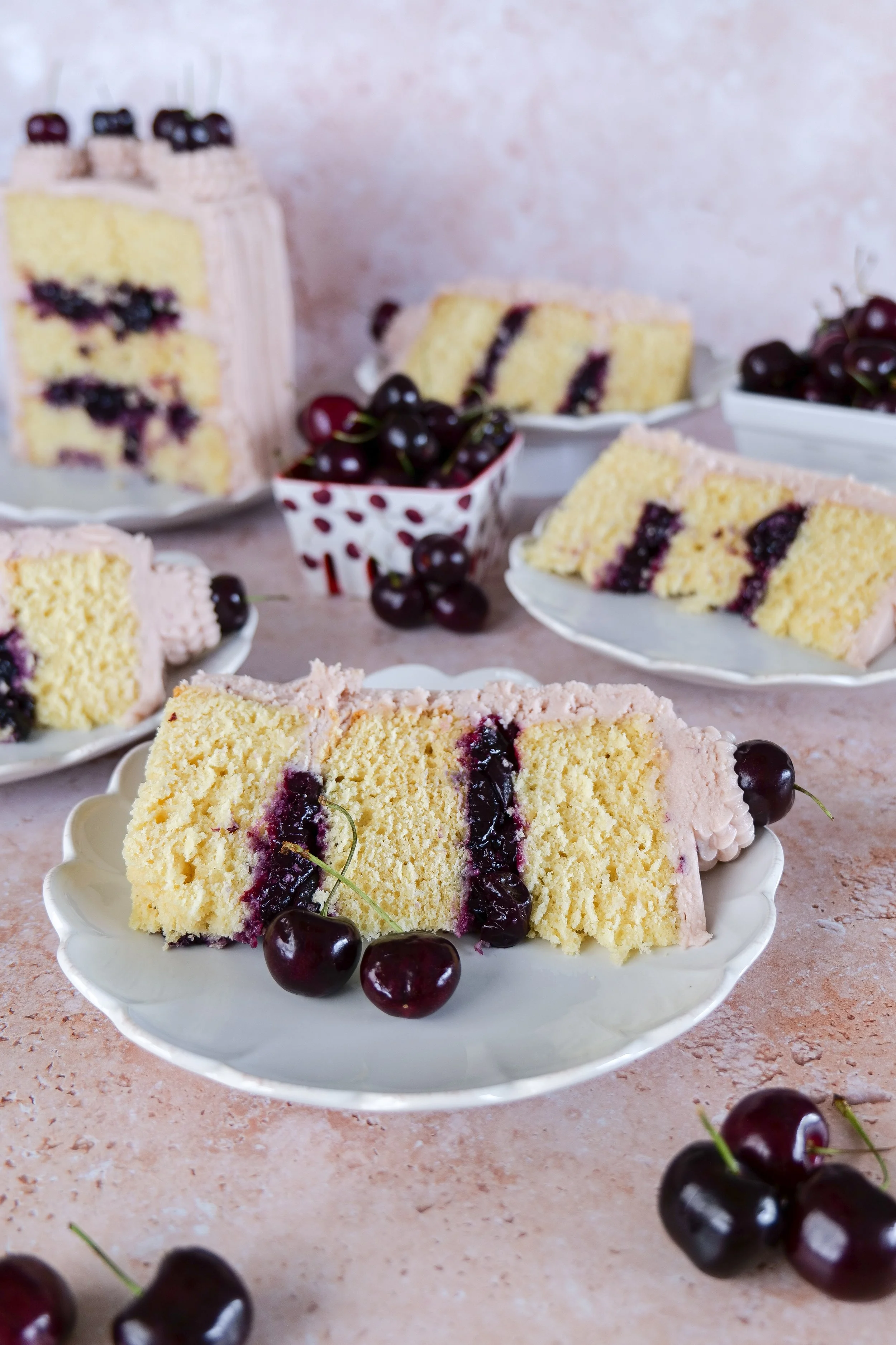 Fresh cherries styled beside slices of homemade vanilla bean cherry cake.