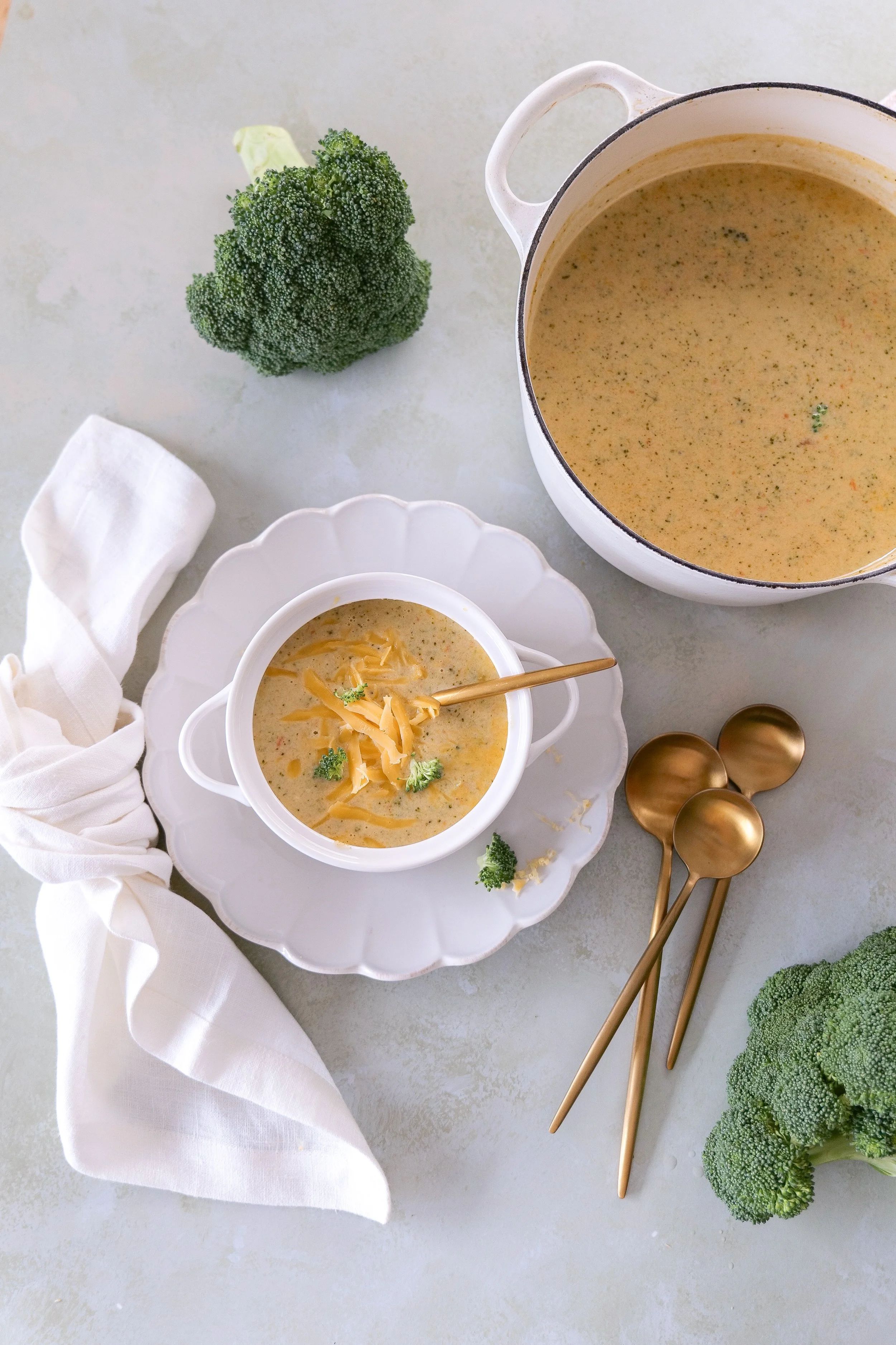 Cozy bowl of creamy broccoli cheddar soup topped with additional cheddar cheese.