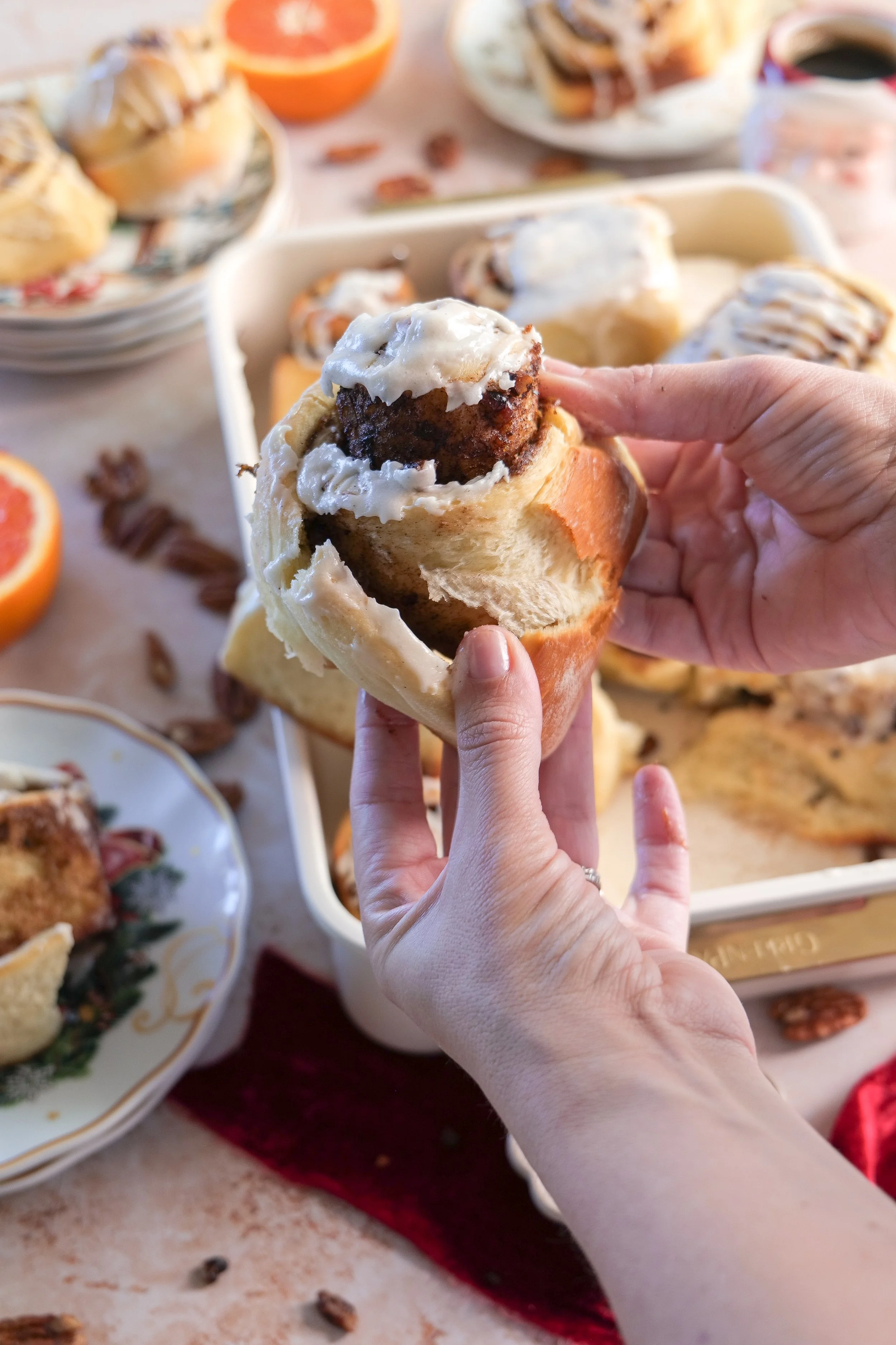Close-up of soft orange pecan cinnamon rolls with swirls of cinnamon filling and vanilla bean glaze.