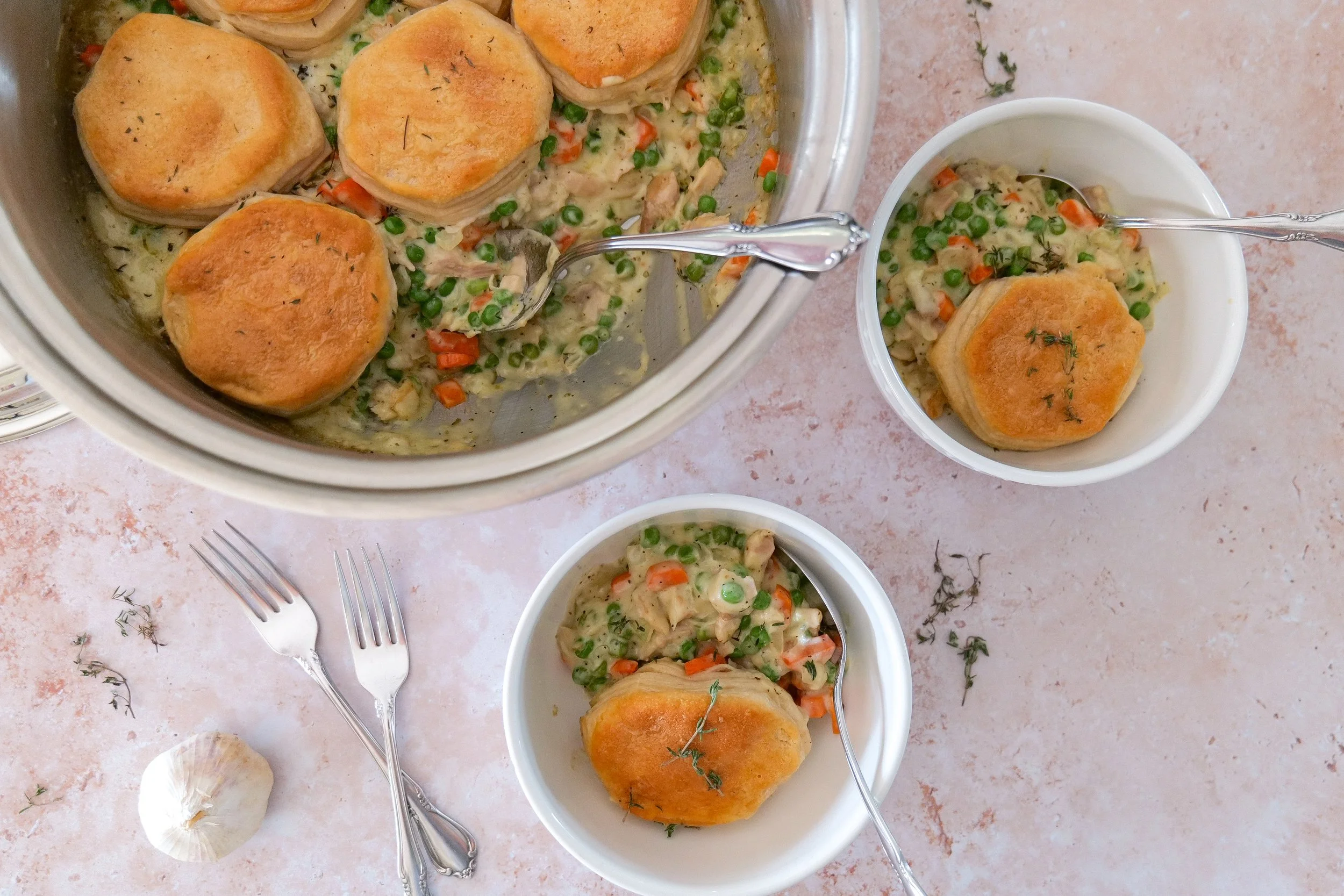 Creamy chicken pot pie filling cooking in a skillet after adding broth, cream, herbs, and vegetables.