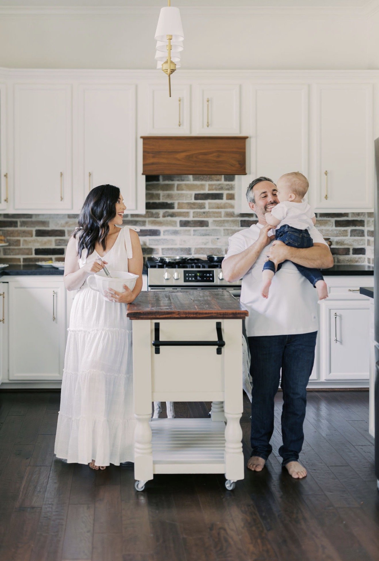 Mom mixing in a bowl across the kitchen island from dad holding their baby in their Texas home