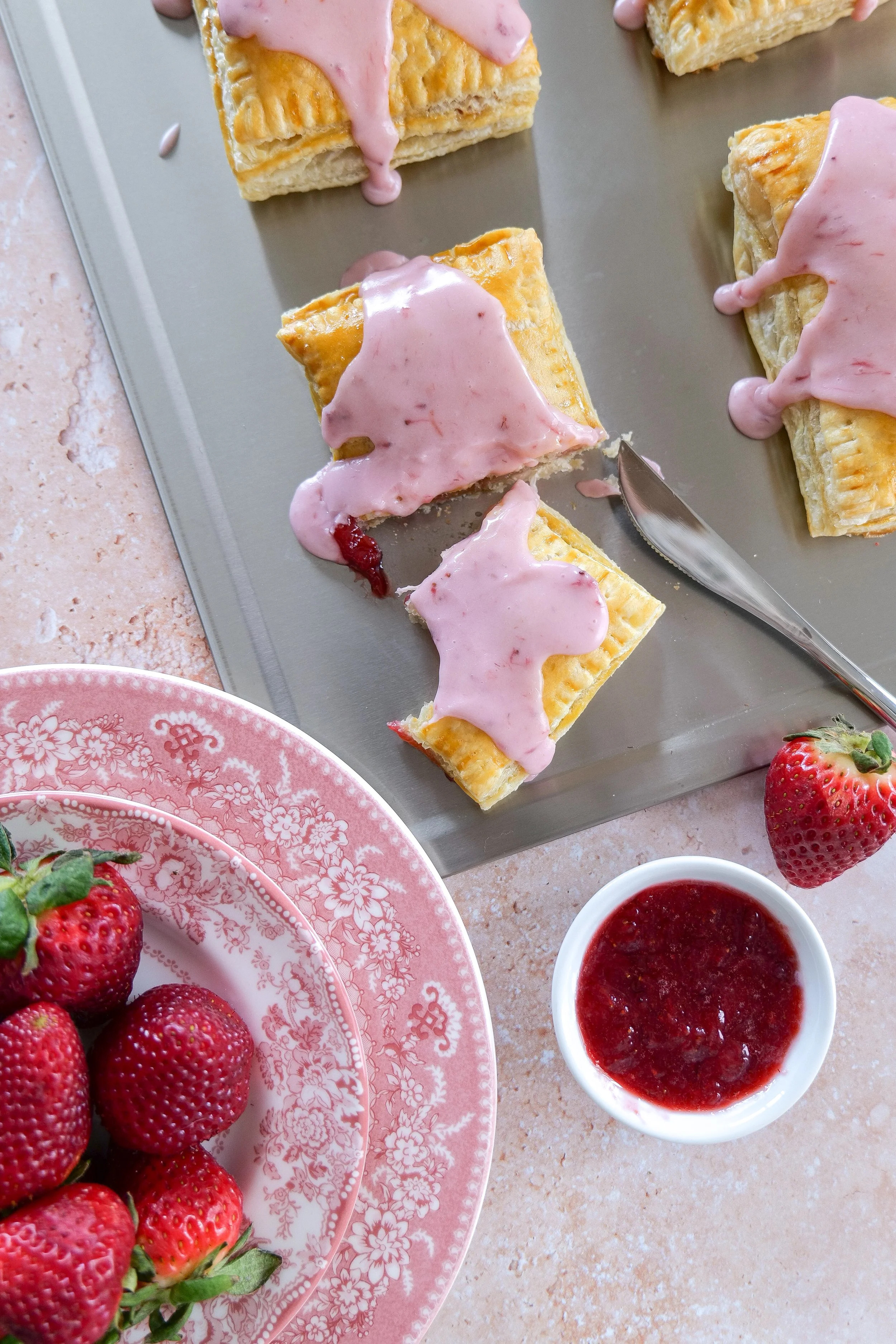 homemade strawberry puff pastry pop tarts featuring a golden, flaky crust filled with jam and topped with a pink glaze