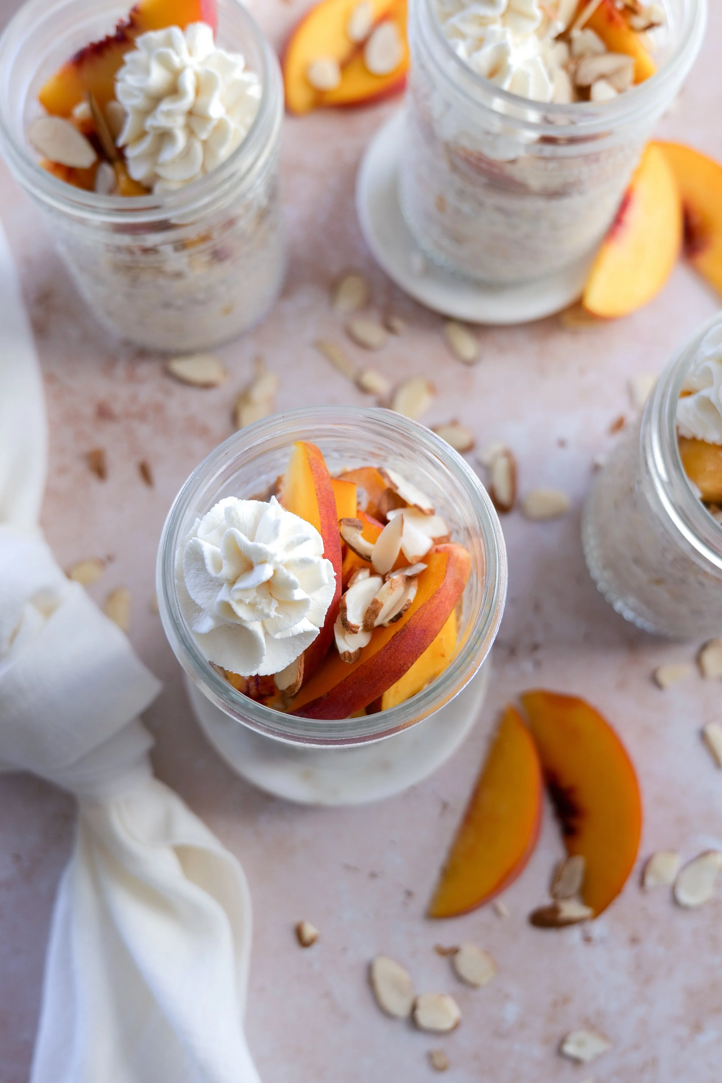 Creamy Peach Cobbler Overnight Oats in a mason jar with fresh peaches.