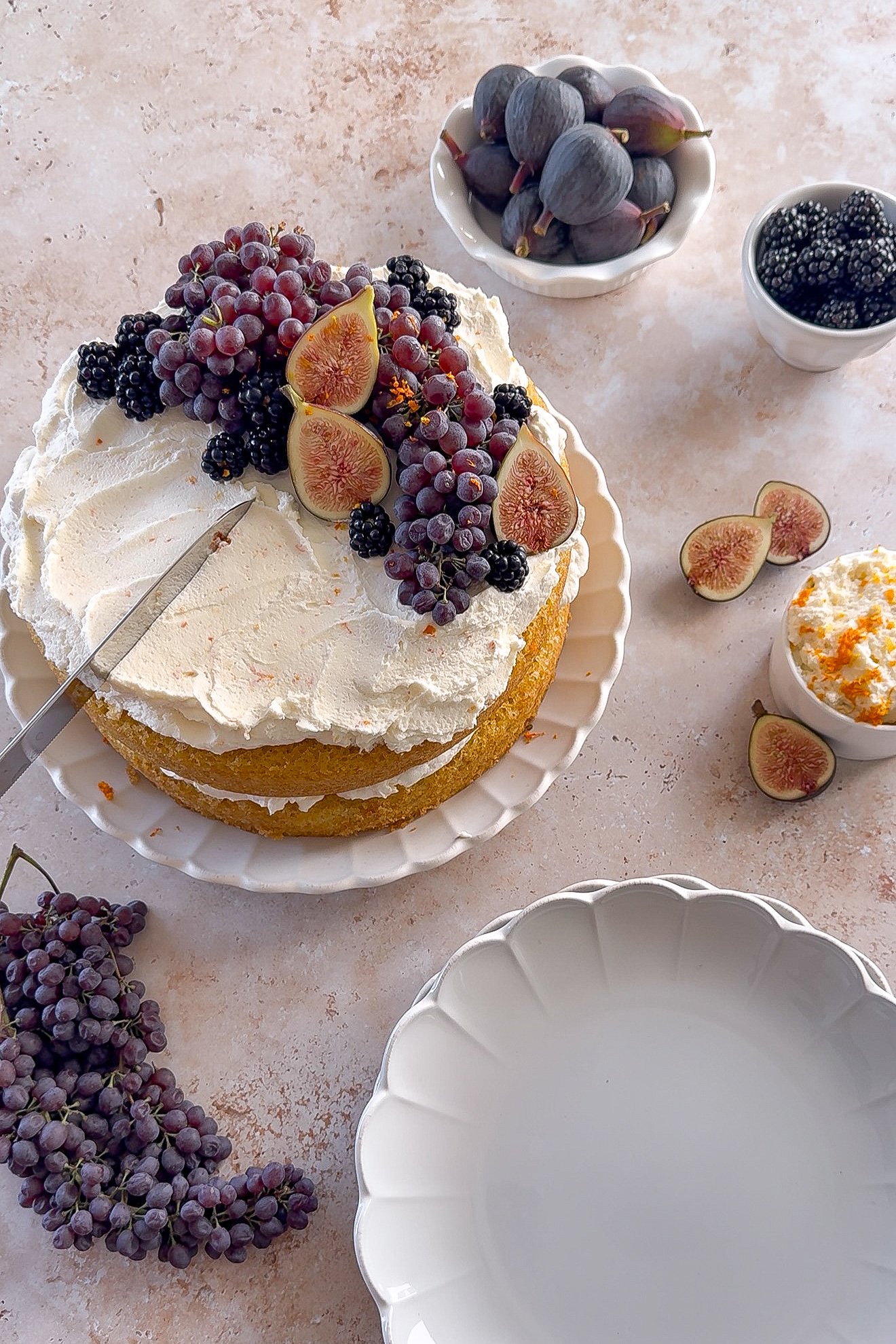 Knife cutting into orange olive oil cake layered with mascarpone cream