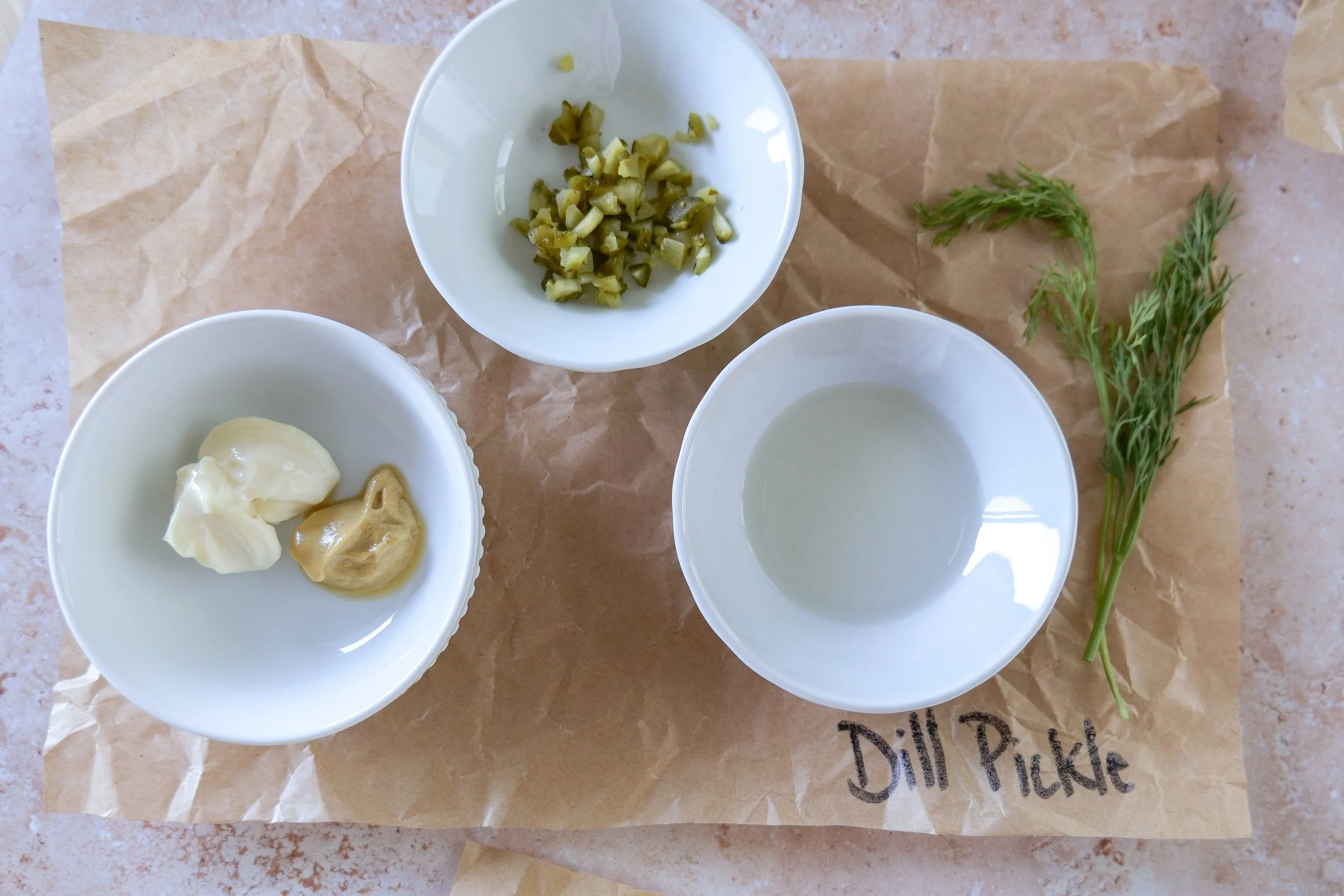 Ingredients for dill pickle egg salad including hard-boiled eggs, dill pickles, mayonnaise, mustard and fresh dill.