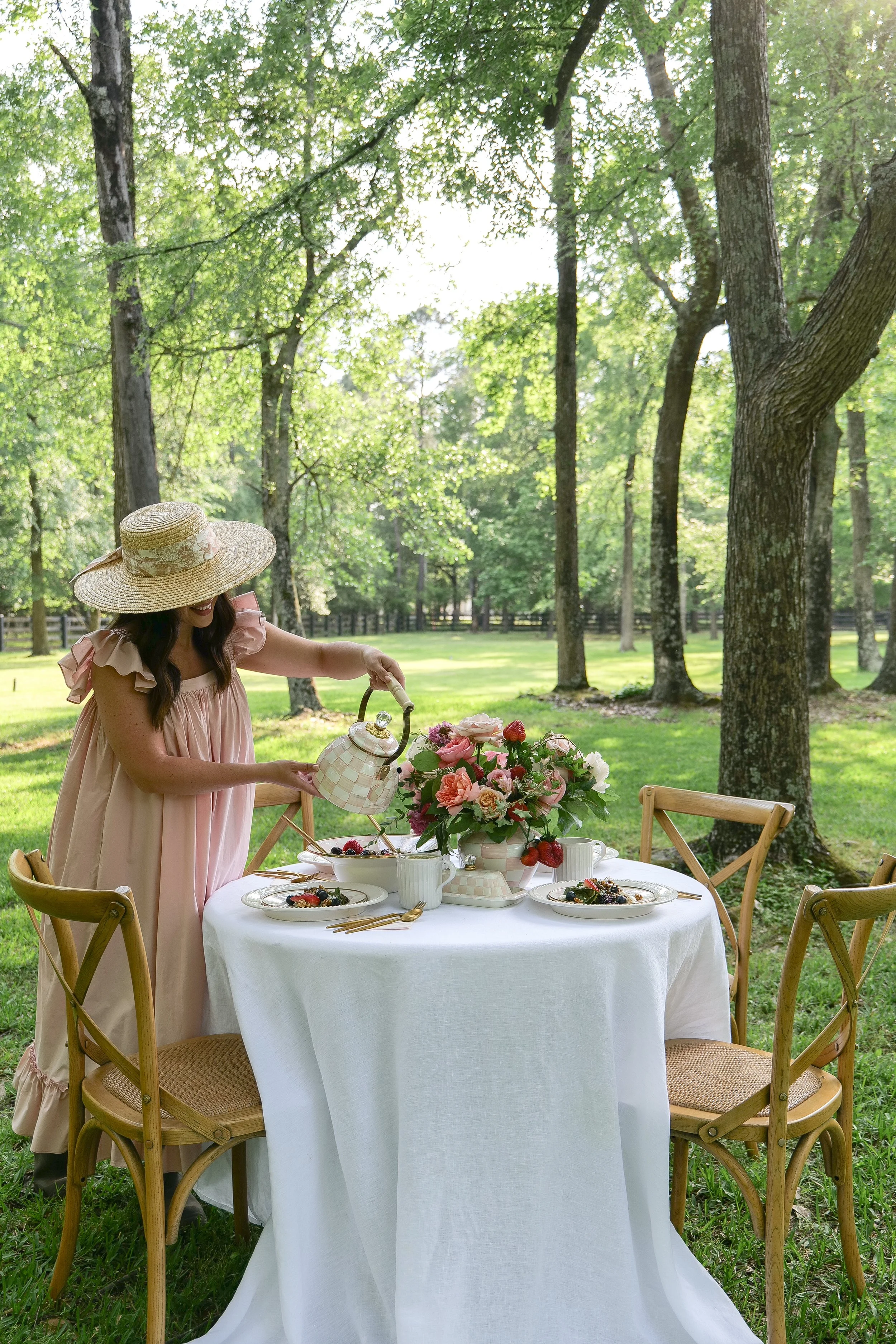 Outdoor summer garden lunch table surrounded by trees and greenery with fresh berry salad.