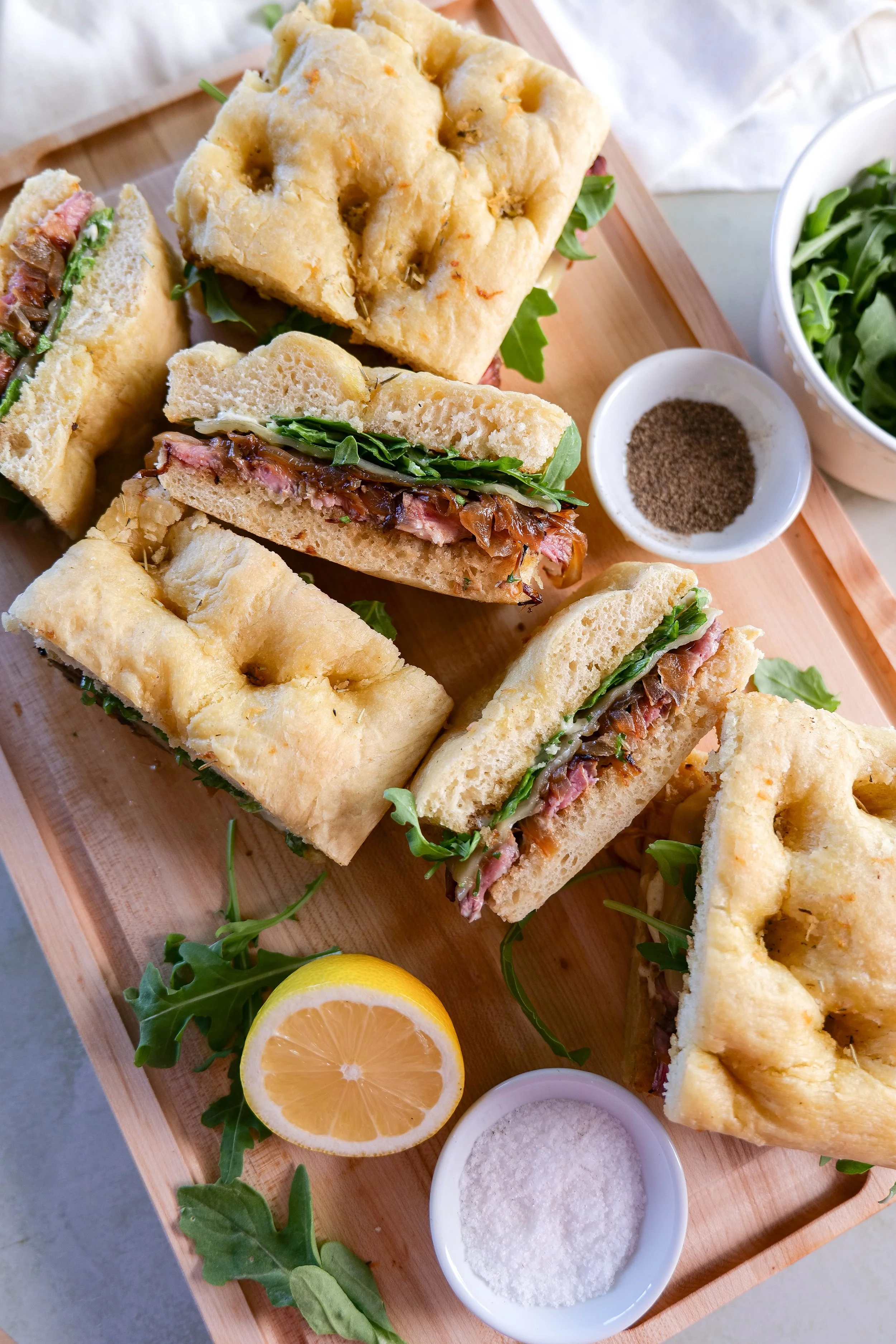 Toasted focaccia sandwich filled with sliced ribeye and arugula