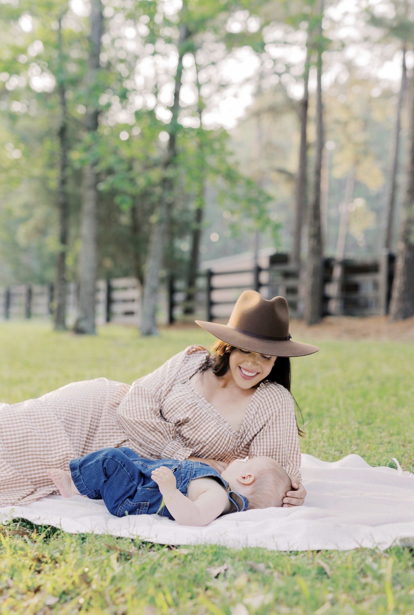 Mom and baby lying together on a blanket and looking at each other outside on their Texas property