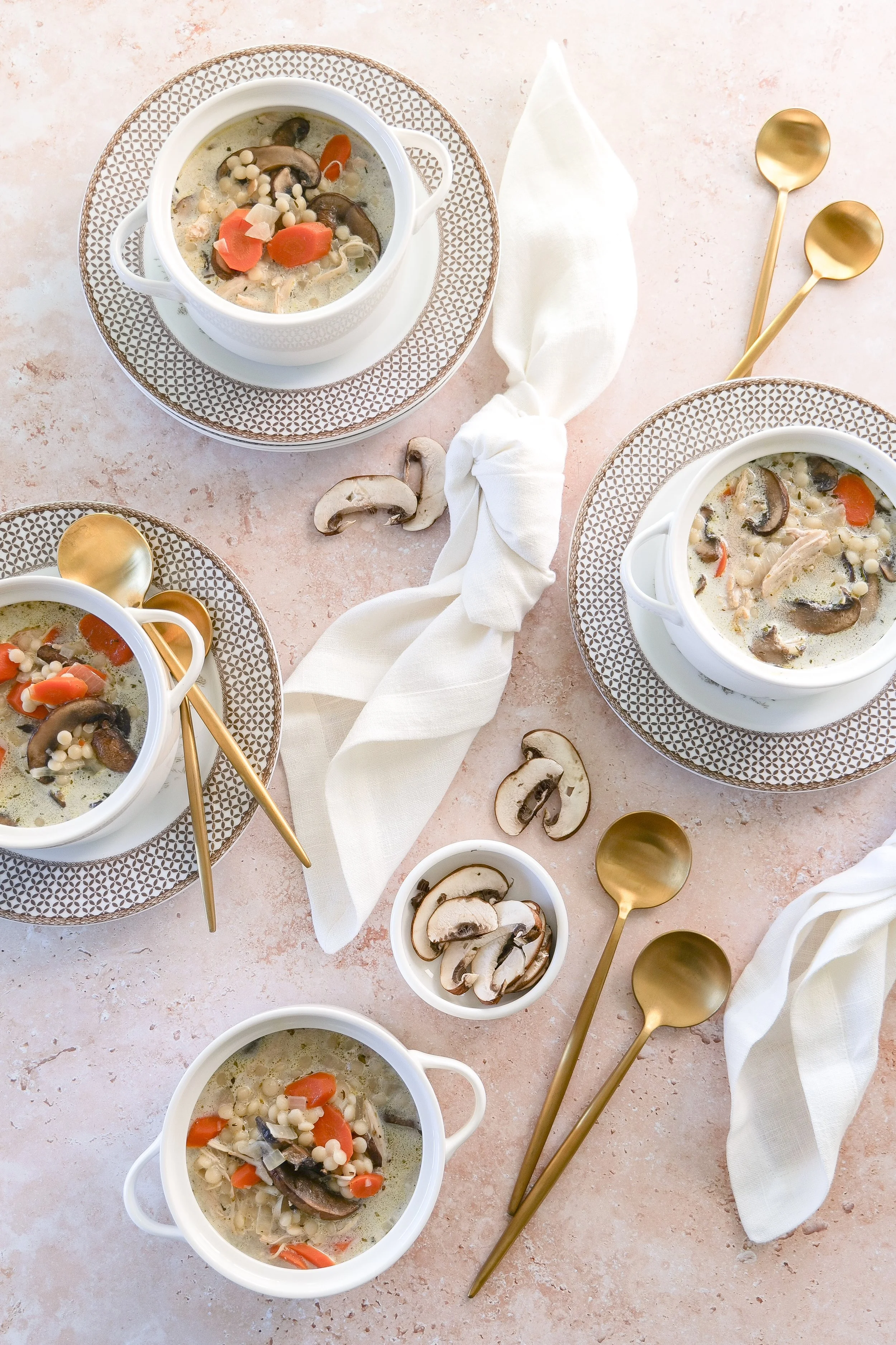 Bowl of slow cooker creamy chicken and mushroom couscous soup with carrots and tender shredded chicken.
