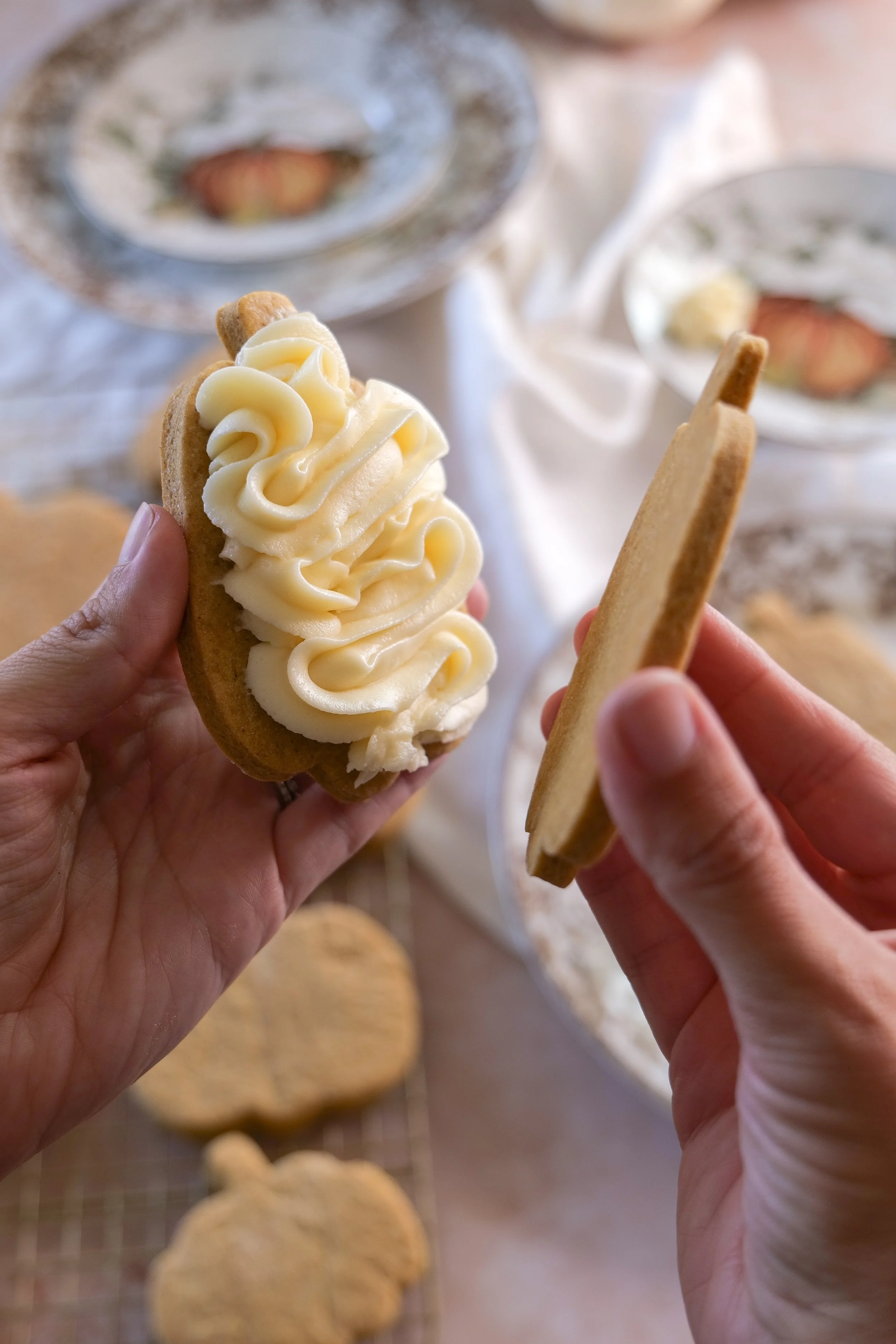 Pumpkin sandwich cookie being assembled with cream cheese filling