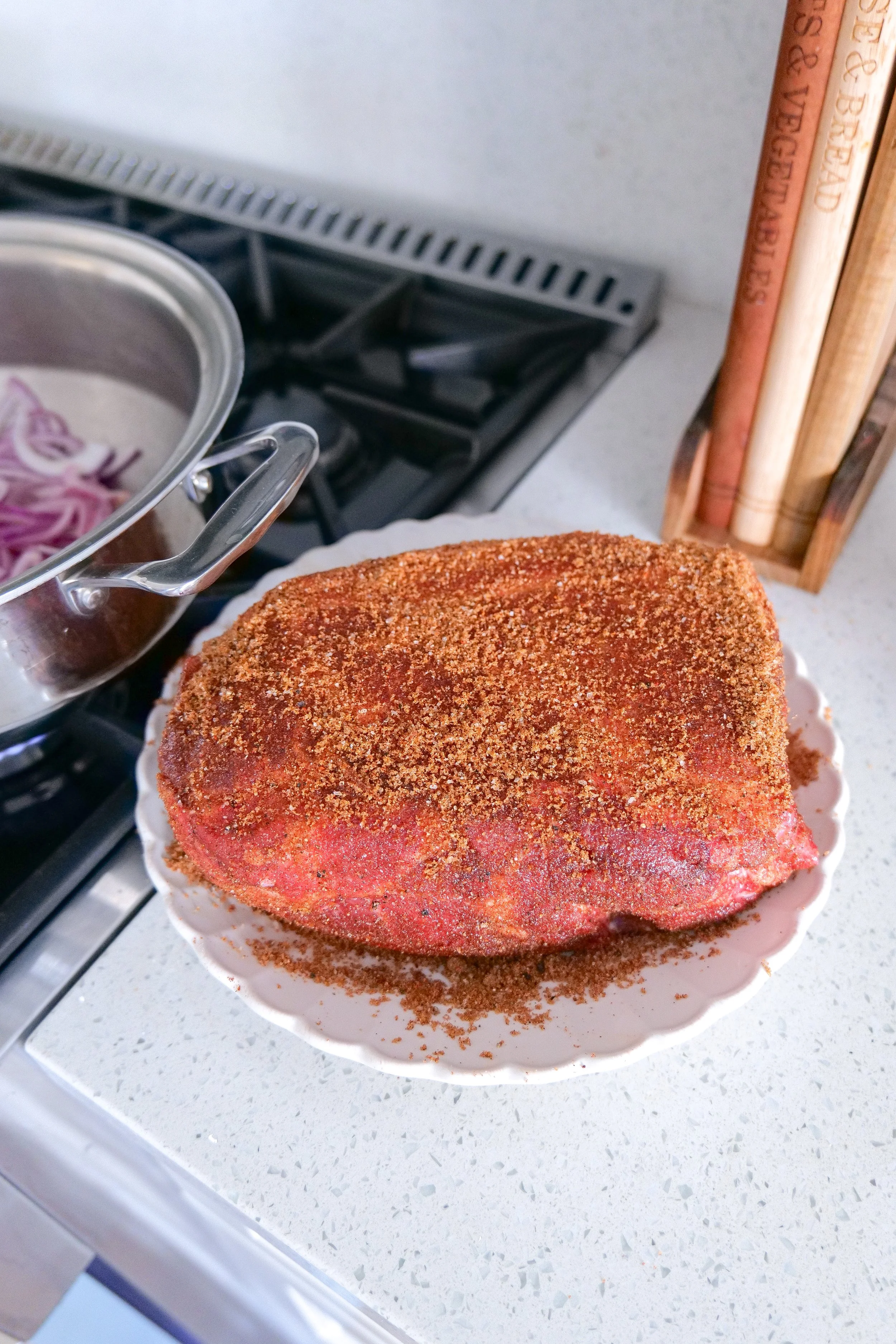 Seasoned pork shoulder with sliced red onion prepared in the slow cooker before cooking.