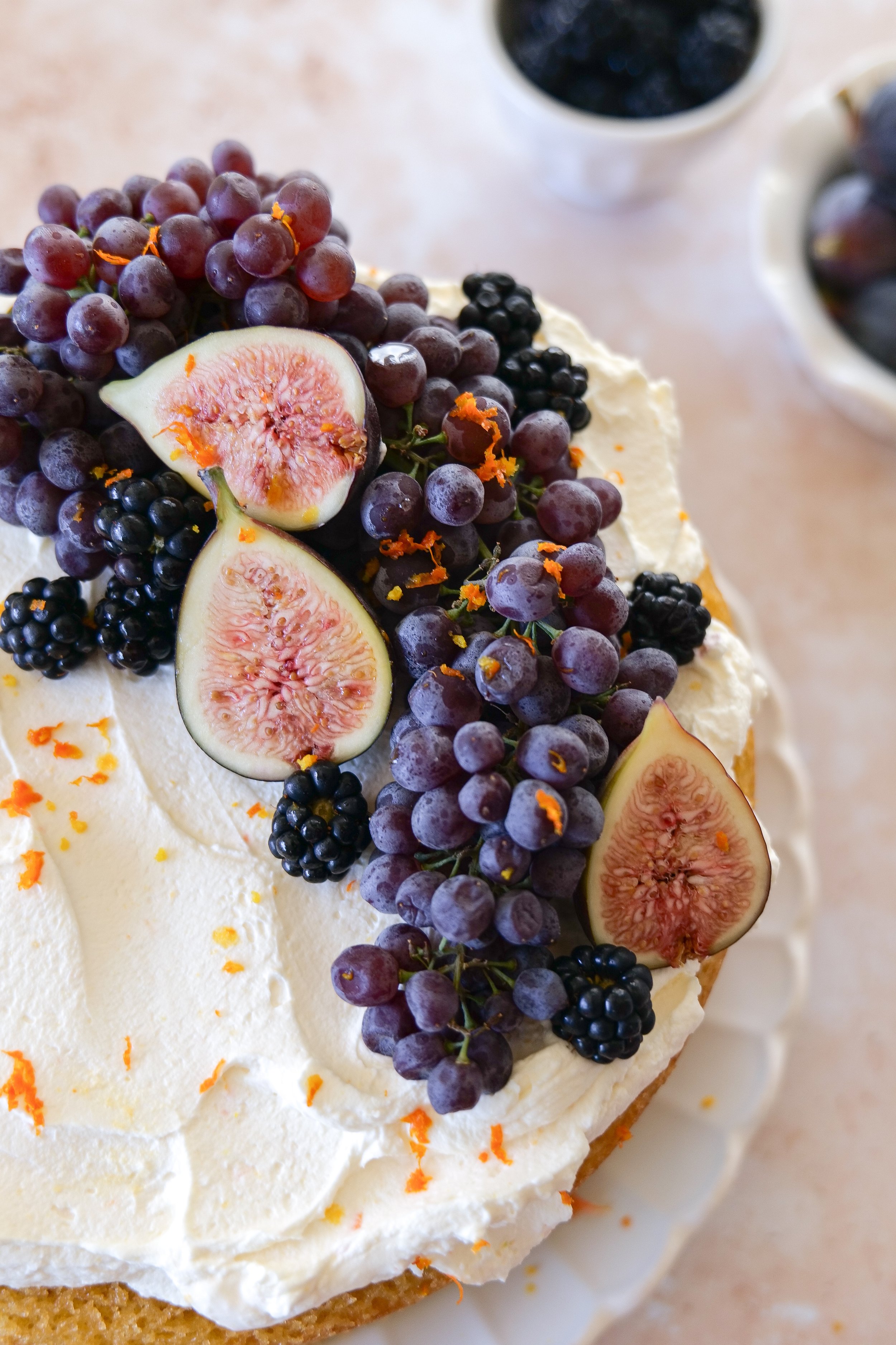 Side view of orange olive oil cake with exposed golden layers, mascarpone cream, and fresh fruit