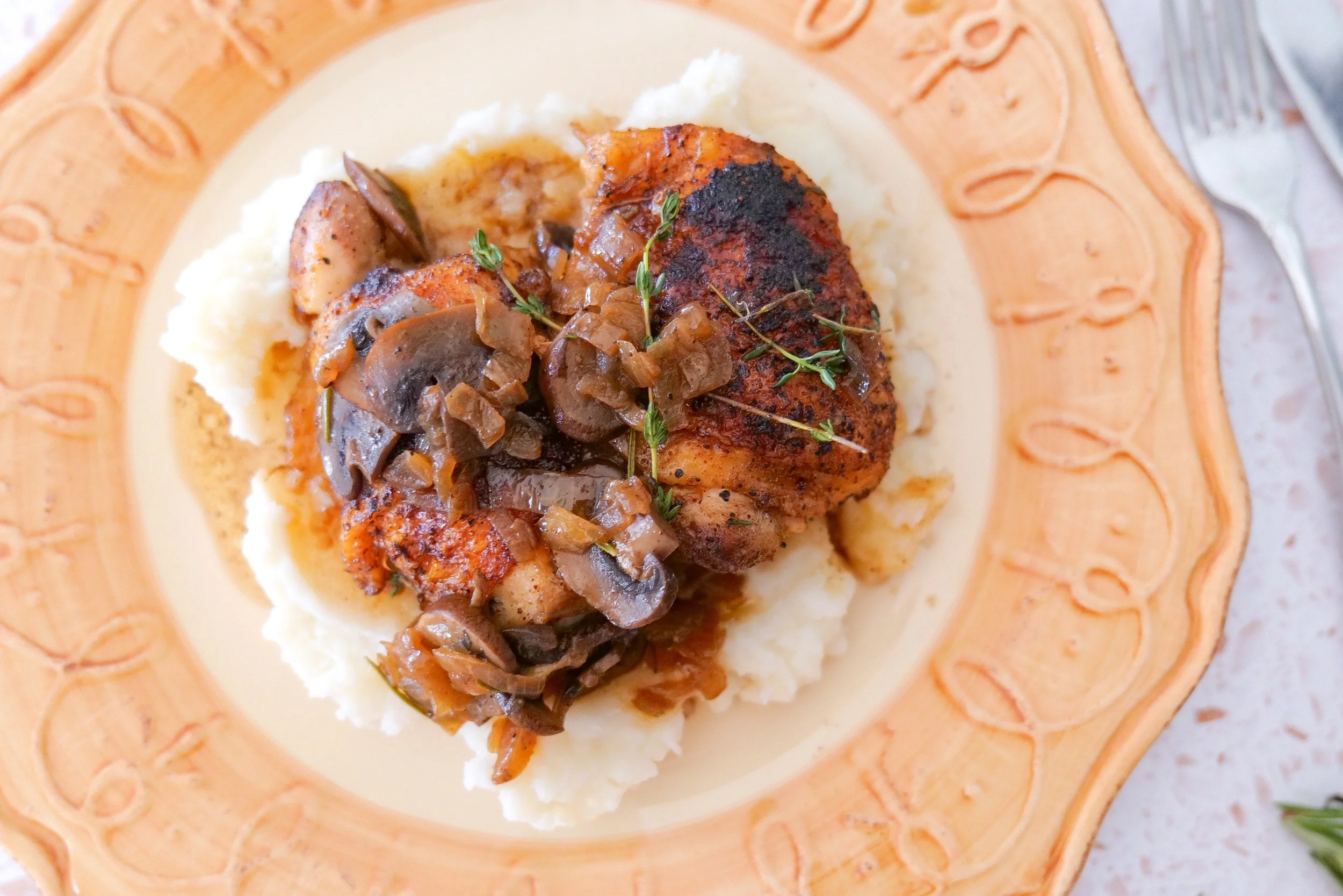 Crispy bone-in chicken thighs surrounded by savory mushrooms and onions.