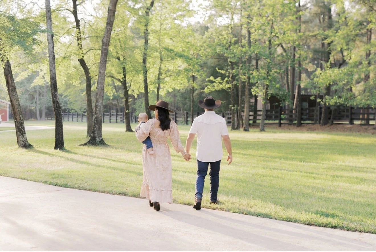 Family walking through their Texas property with a red barn and trees in the background