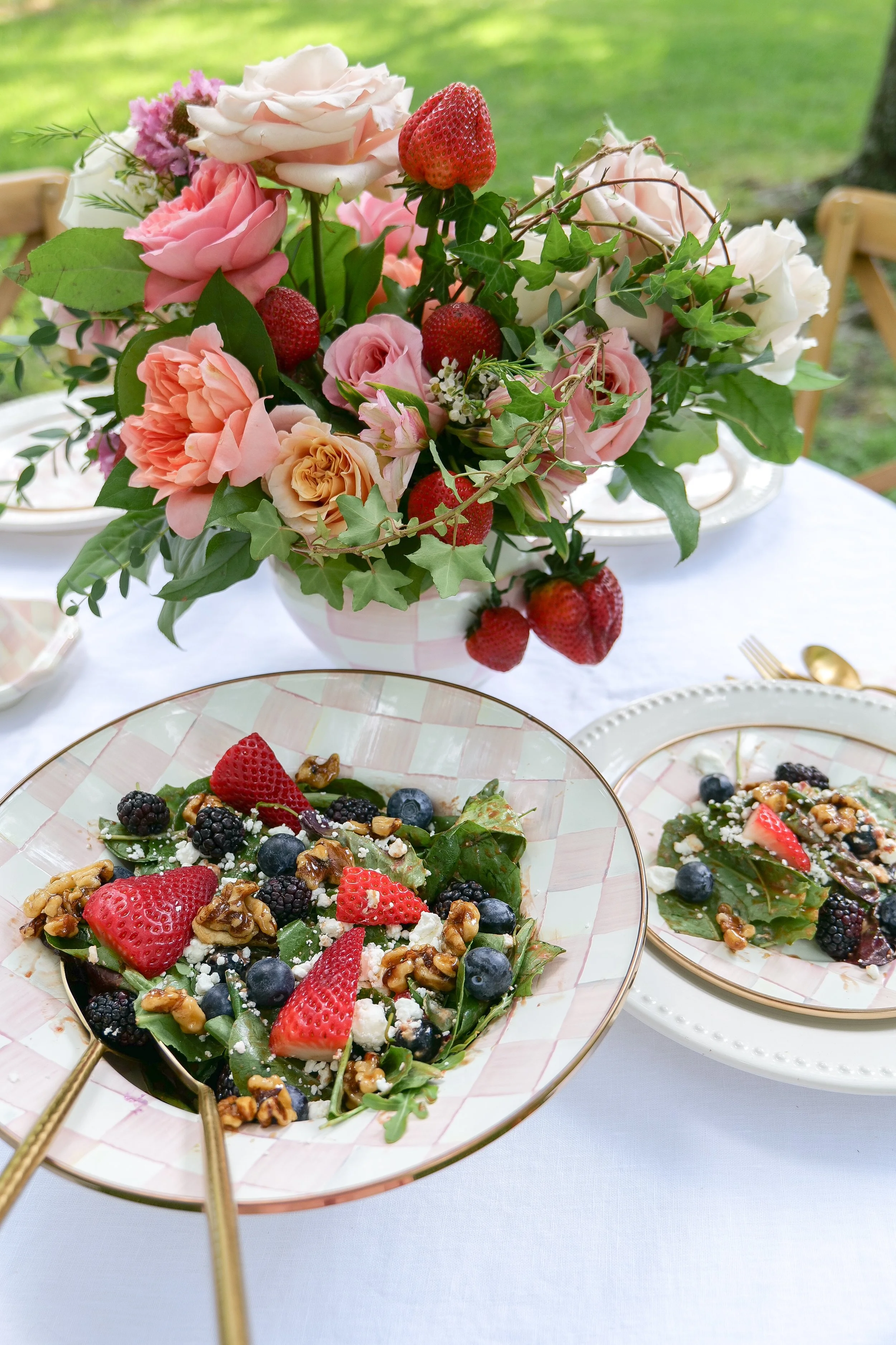 Overhead view of berry spinach salad topped with goat cheese, fresh berries and candied walnuts.
