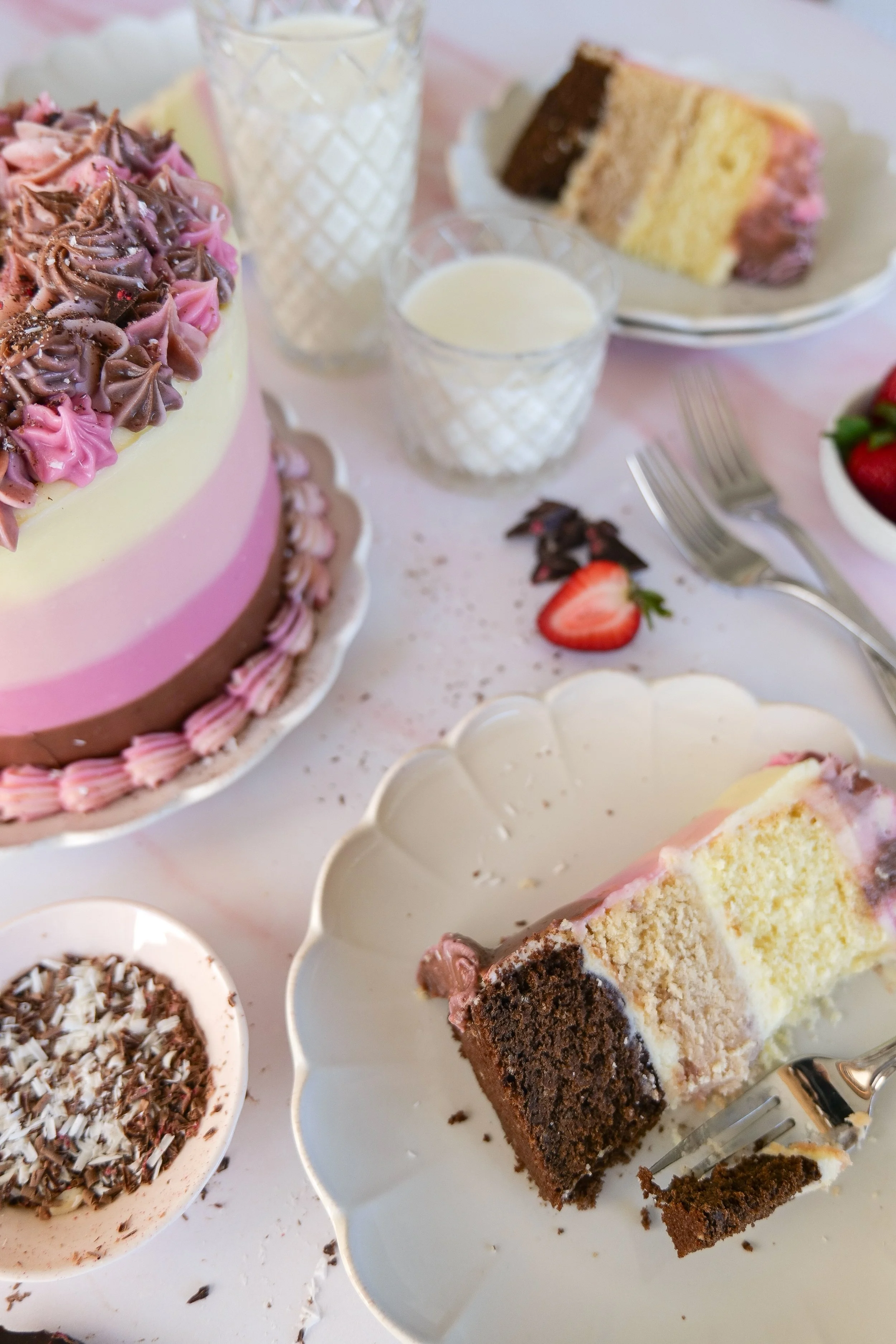 Layered Neapolitan cake with chocolate, vanilla, and strawberry cake layers covered in cream cheese frosting.