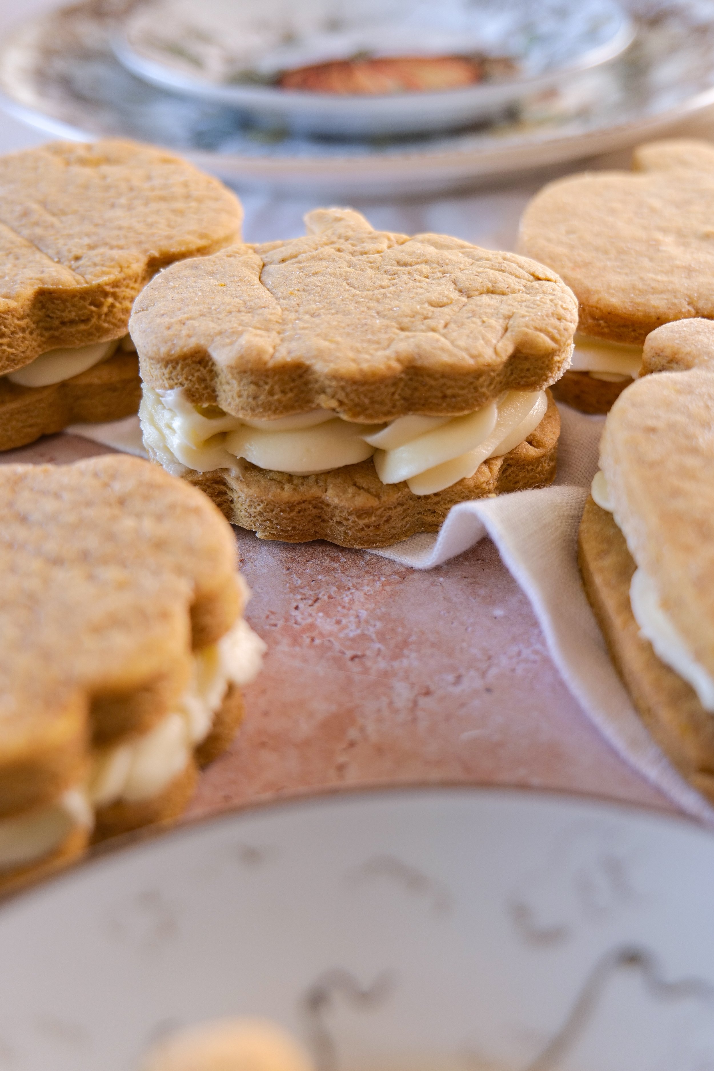 Close-up of a pumpkin sandwich cookie with thick cream cheese filling