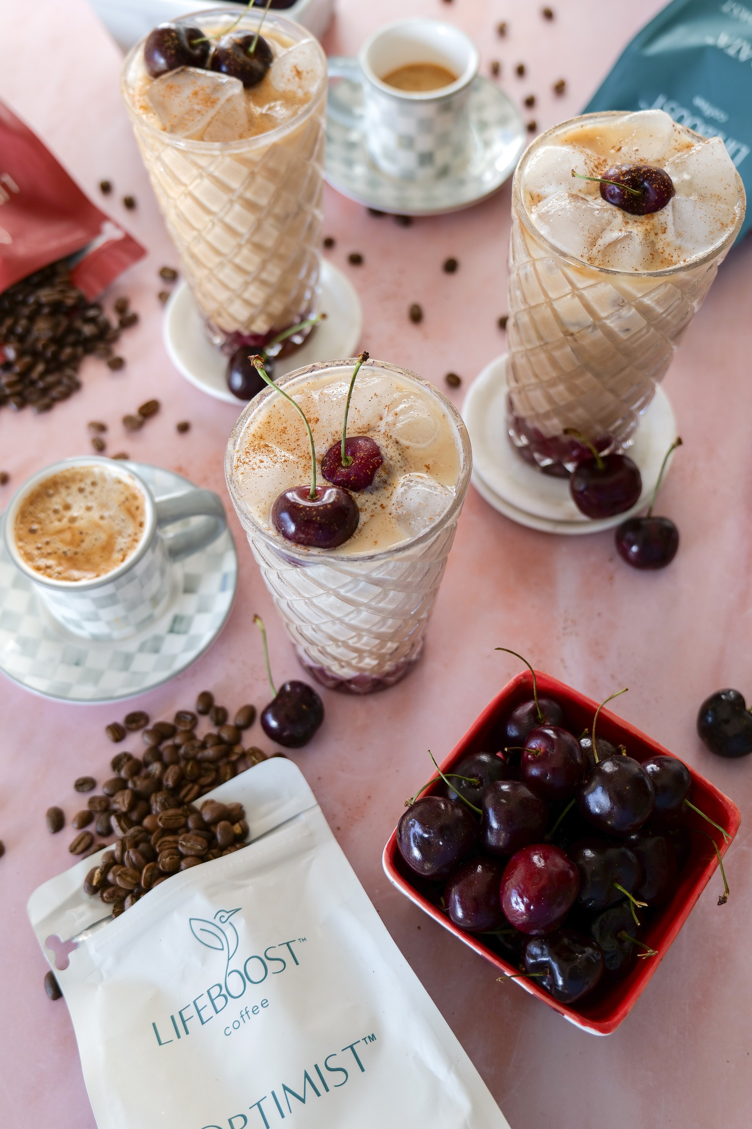Iced latte made with homemade cherry syrup, espresso, milk, and sweet cold foam.